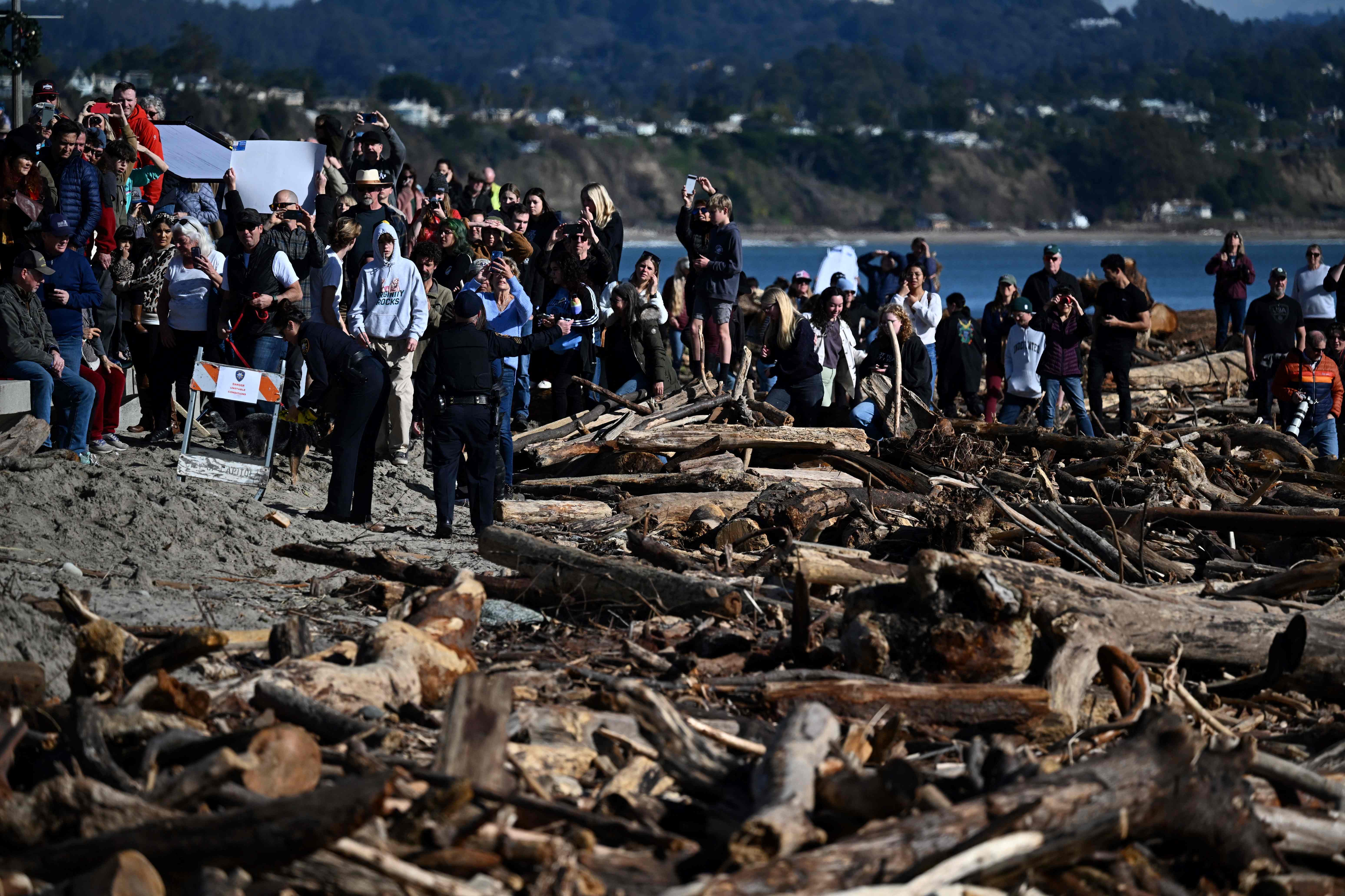 People look on as President Joe Biden surveys damage caused by recent heavy storms