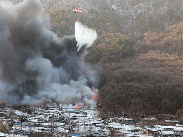 <p>Firefighters try to extinguish a fire at the Guryong village, one of South Korea’s last remaining slums, in southern Seoul</p>