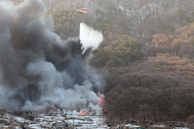 <p>Firefighters try to extinguish a fire at the Guryong village, one of South Korea’s last remaining slums, in southern Seoul</p>