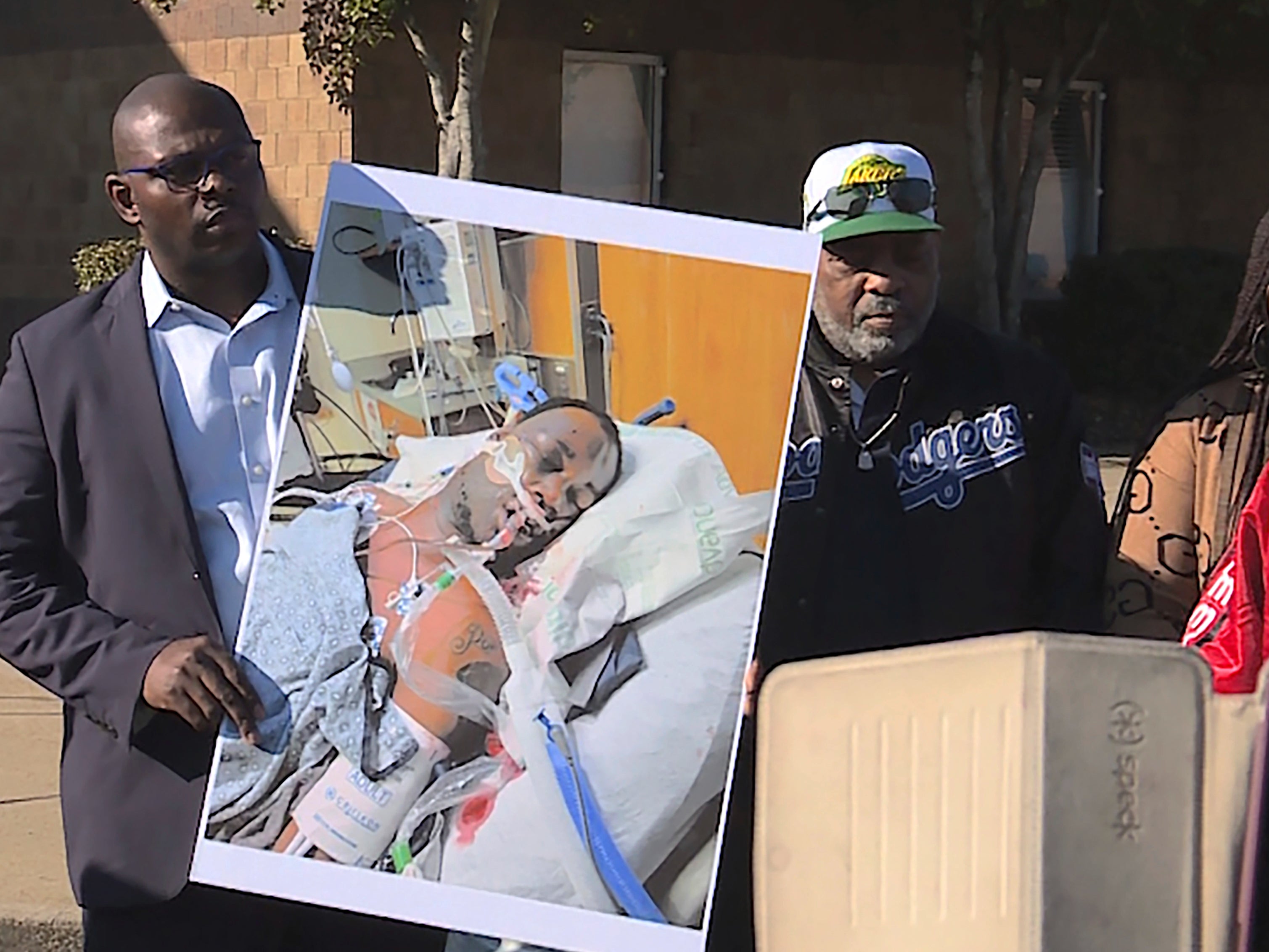 Tyre Nichols' stepfather Rodney Wells, center, stands next to a photo of Nichols in the hospital after his arrest, during a protest in Memphis