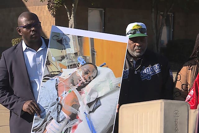<p>Tyre Nichols' stepfather Rodney Wells, center, stands next to a photo of Nichols in the hospital after his arrest, during a protest in Memphis</p>
