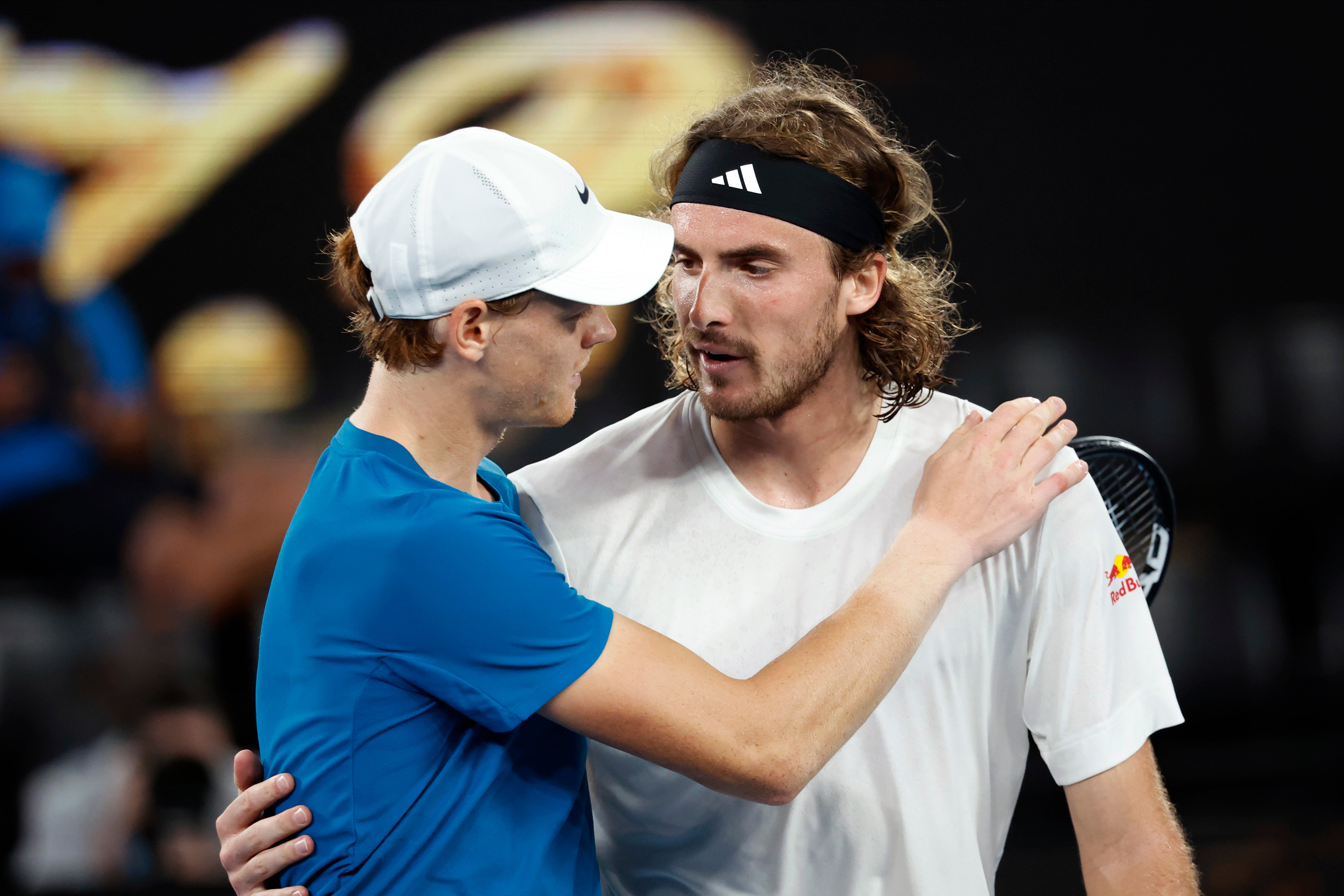 Stefanos Tsitsipas, right, consoles Jannik Sinner at the net after his victory in Melbourne
