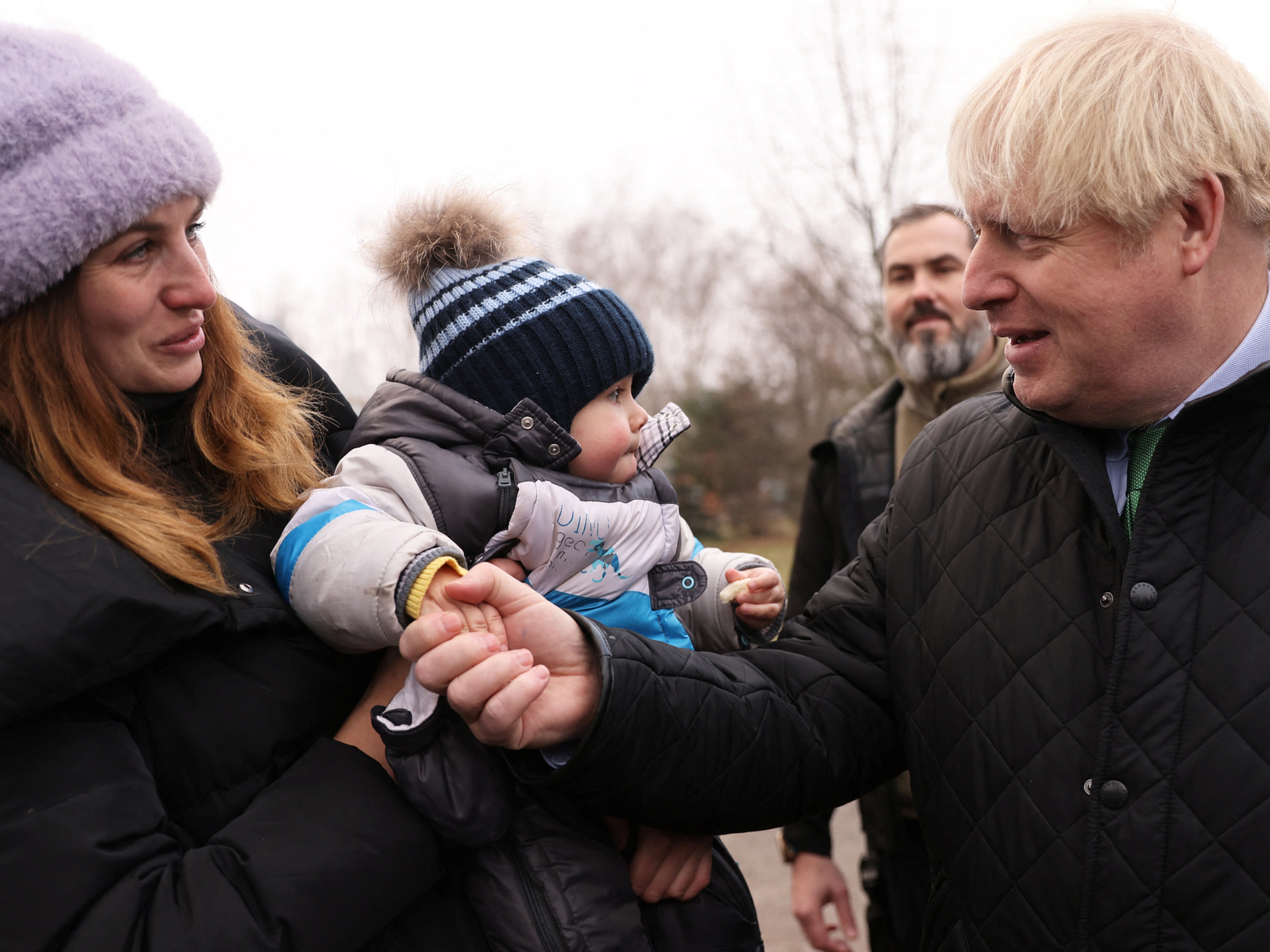 Boris Johnson shakes hands with a baby at a visit to a church in Bucha