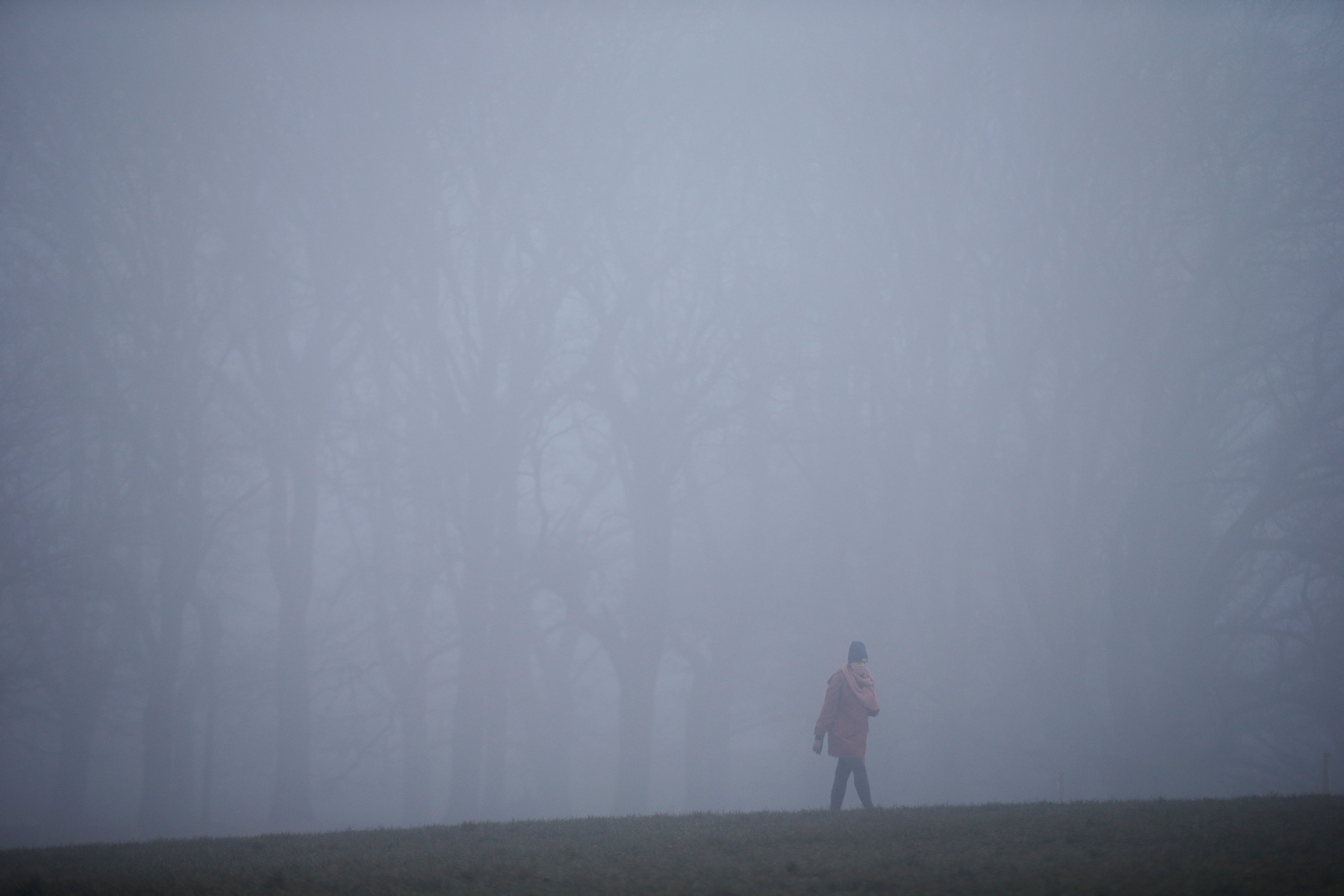 A woman walks in the fog at Parliament Hill in Hampstead Heath during foggy weather