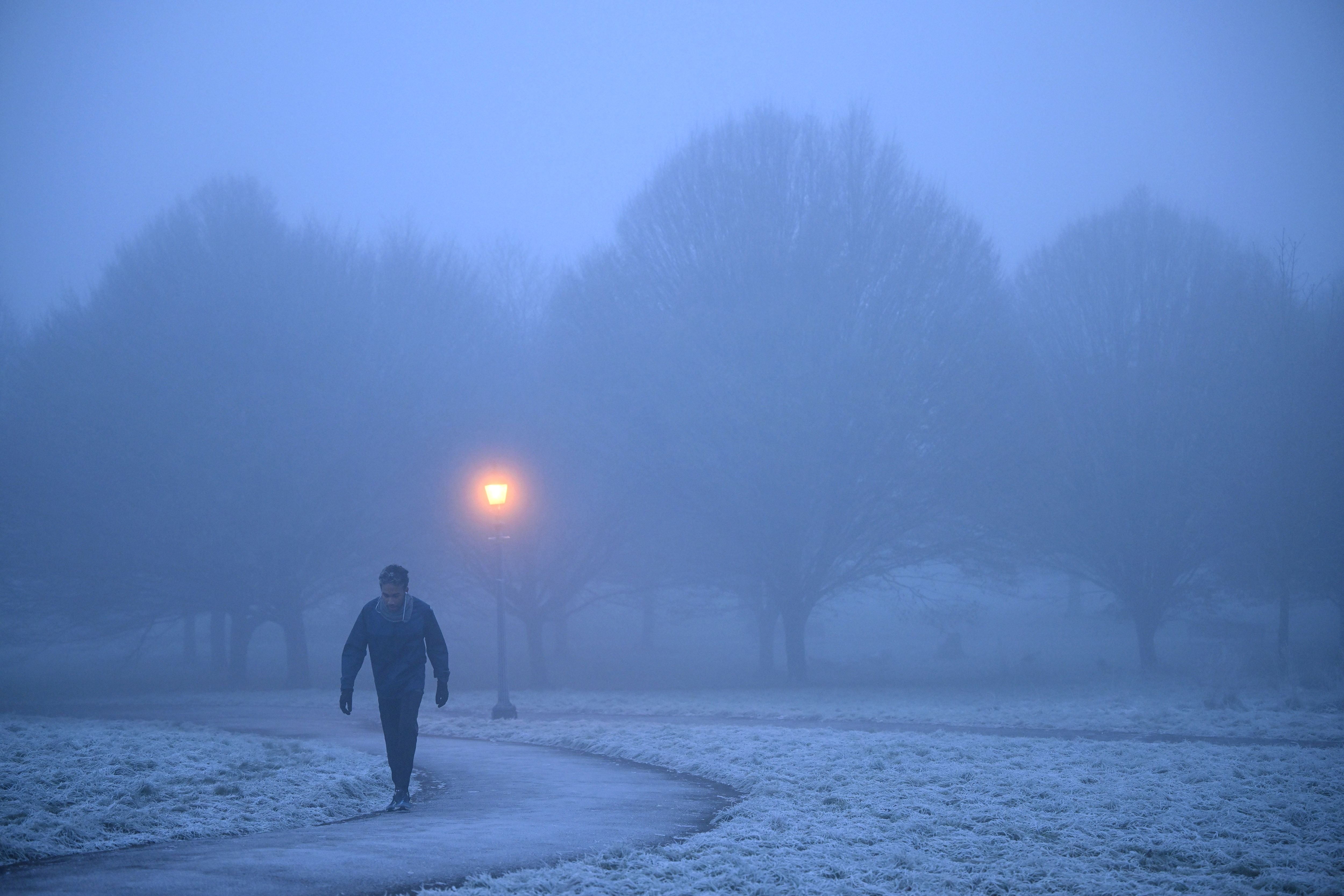 A walker makes their way through fog on a frosty morning at Primrose Hill in north London