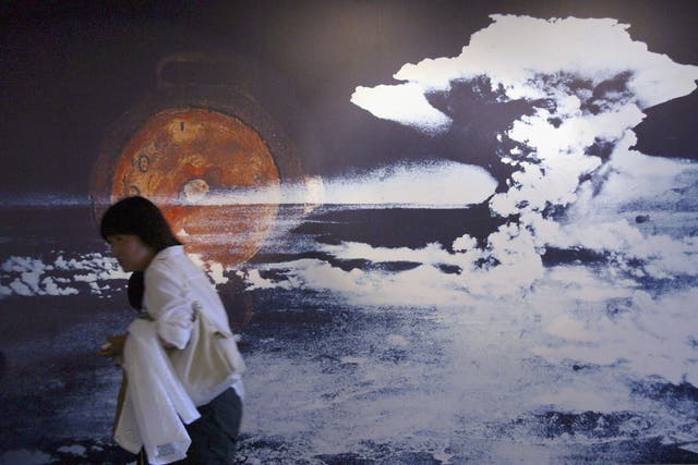 <p>A visitor passes by a wall displaying a picture of the mushroom cloud </p>