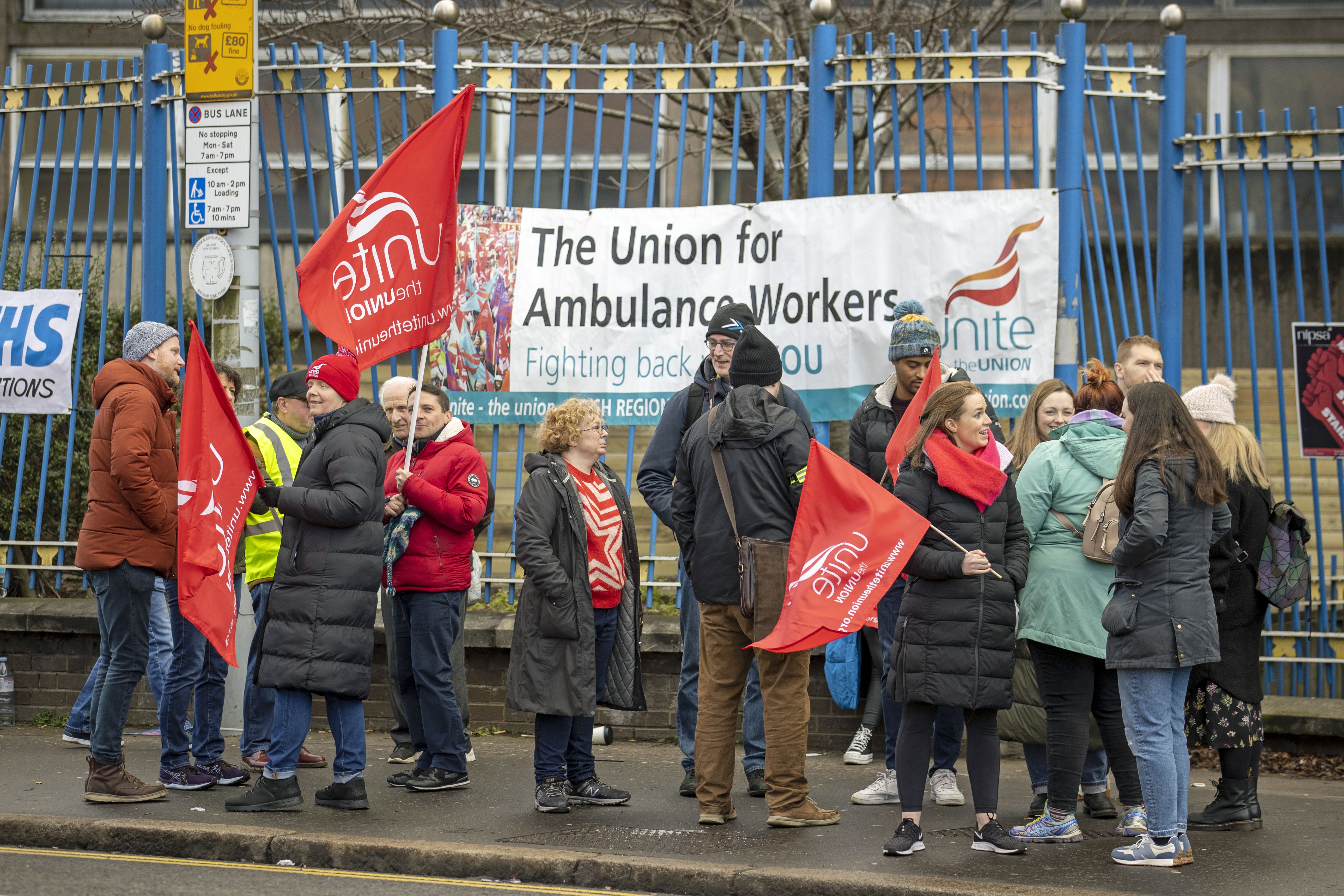 People holding Unite union flags on the picket line outside the Royal Victoria Hospital in Belfast, as thousands of health and social care workers, including paramedics, in Northern Ireland take part in strike action over pay and conditions (Liam McBurney/PA)