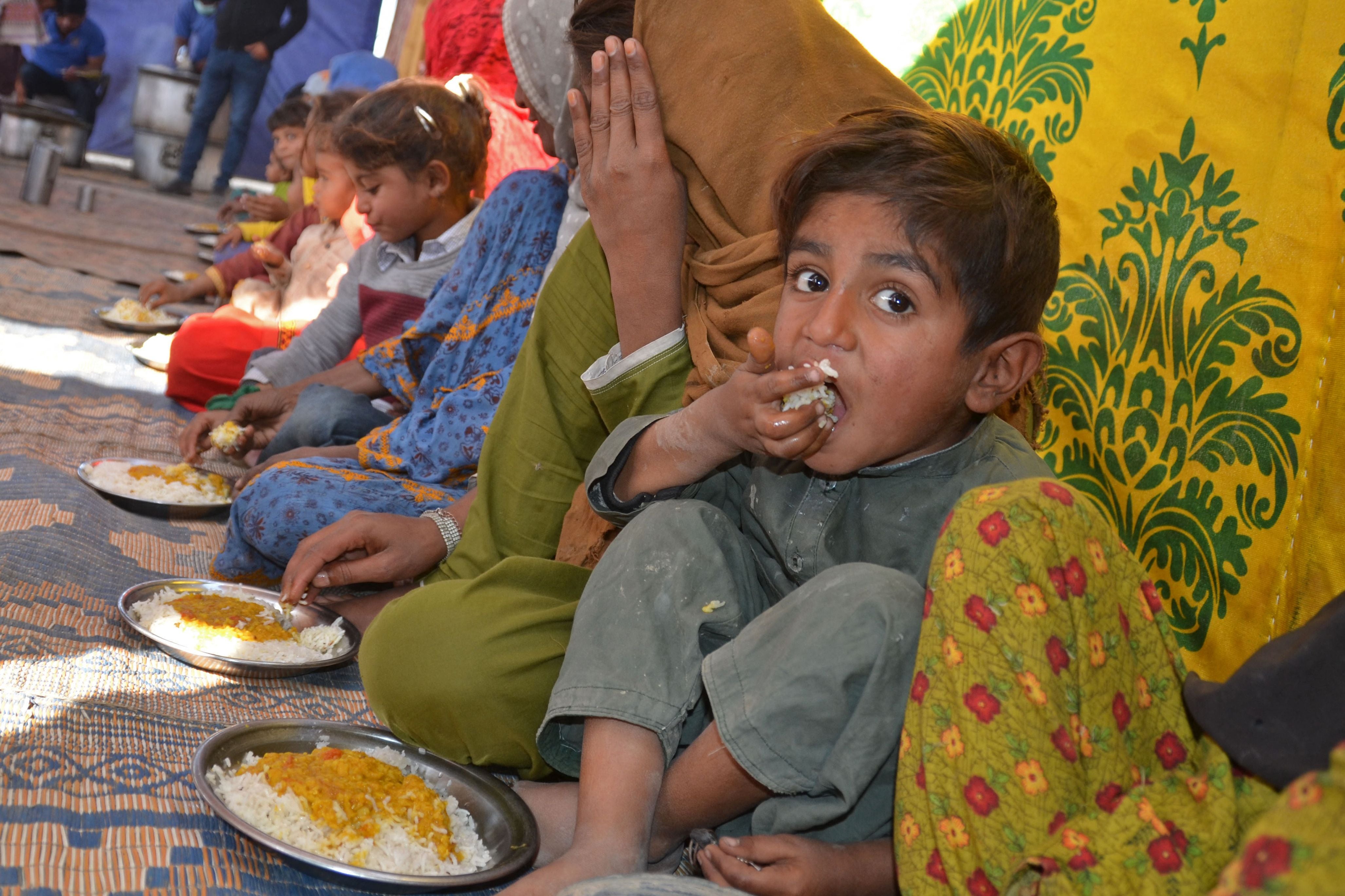 Internally displaced flood-affected people eat free food provided by Bahria Dastarkhwan near a makeshift camp in the flood-hit area of Dera Allah Yar in Jaffarabad district of Balochistan province in Pakistan