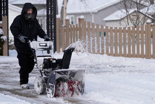 <p>A man cleans the snow off a walkway in front of a house Sunday, Jan. 29, 2023, in Arlington Heights, Illinois</p>
