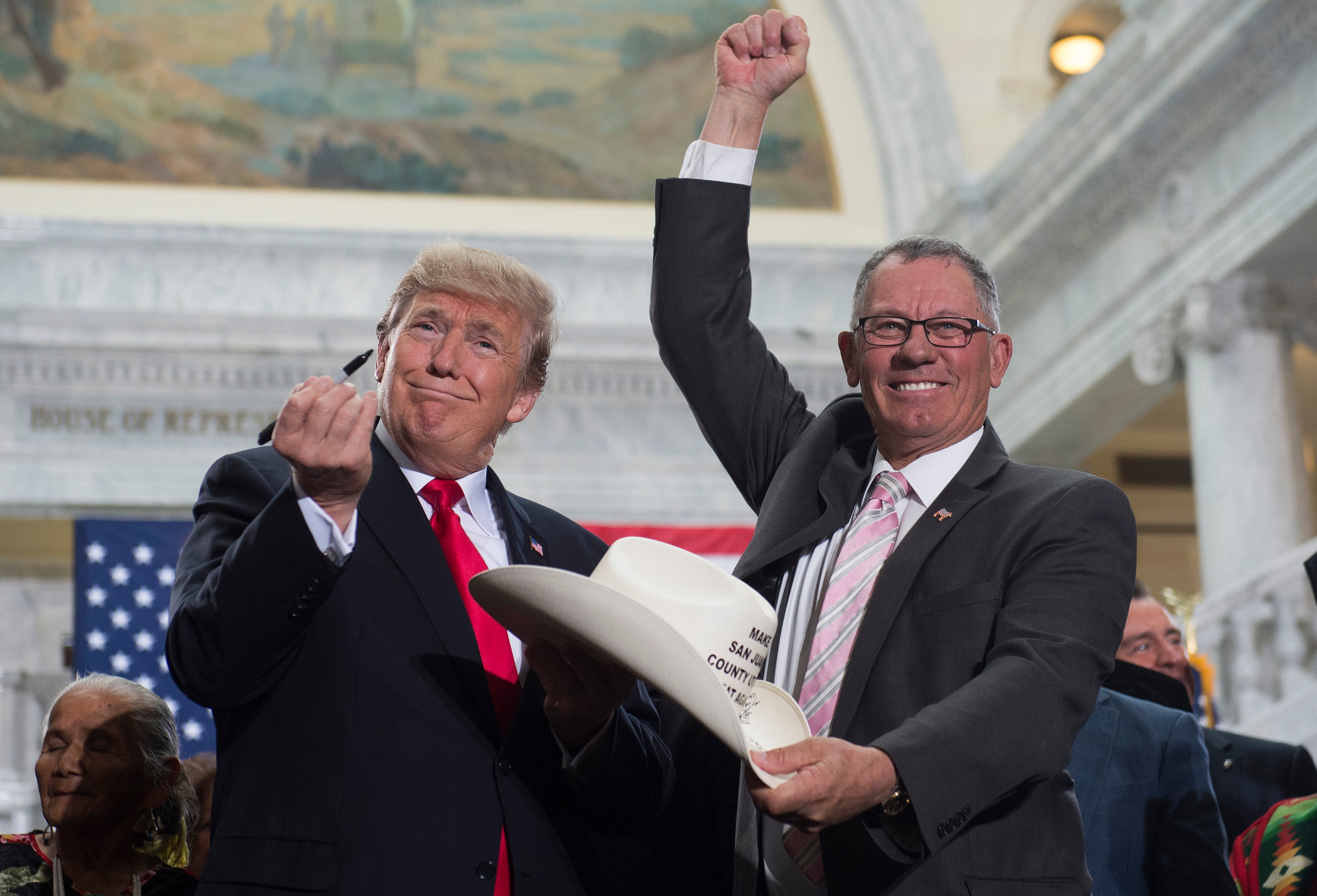 US President Donald Trump holds up a pen after signing the hat of Bruce Adams, Chairman of the San Juan County Commission