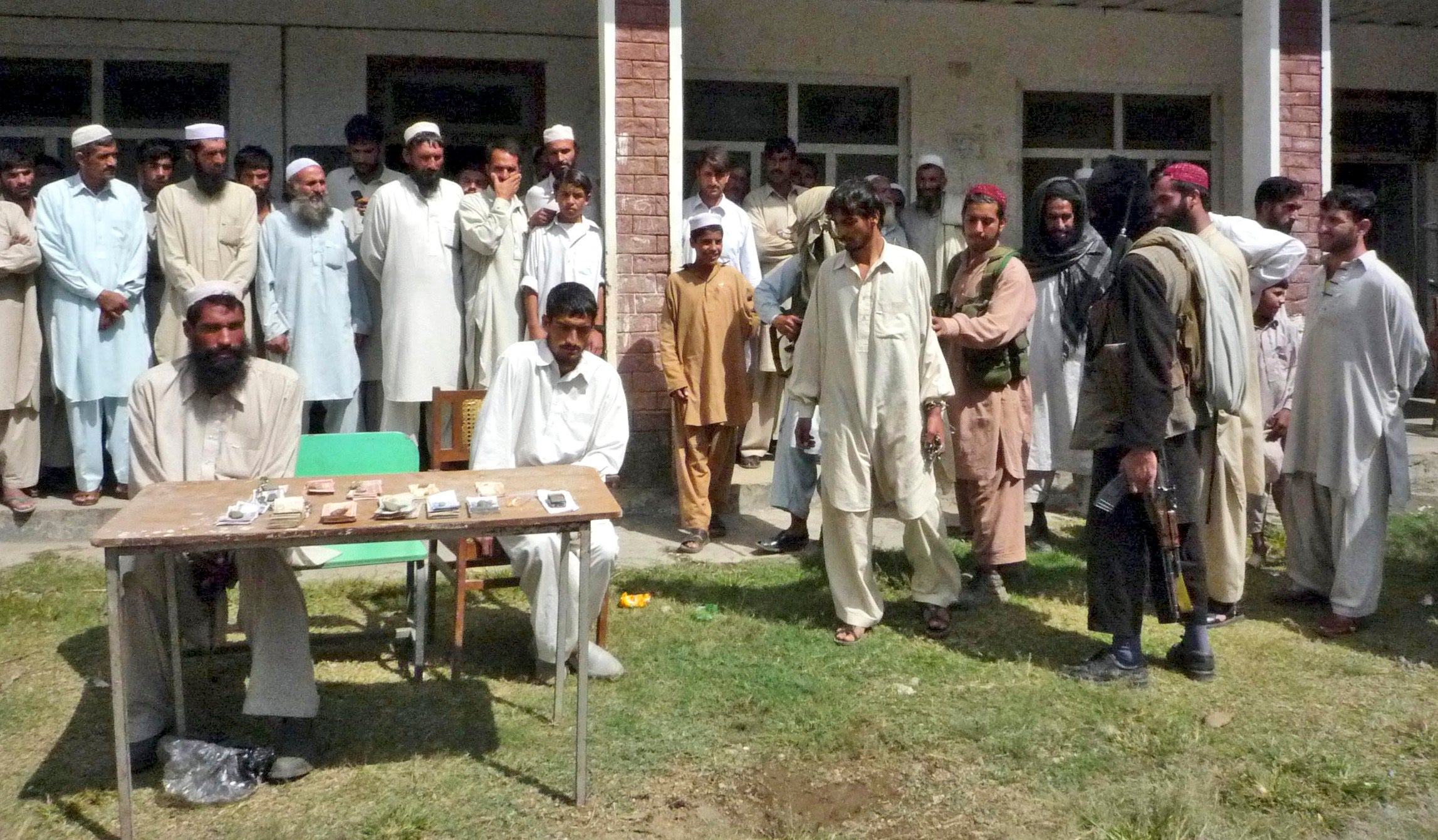 Armed supporters of outlawed militant group Tehreek-e-Taliban Pakistan (right) escort one of three thieves in 2008