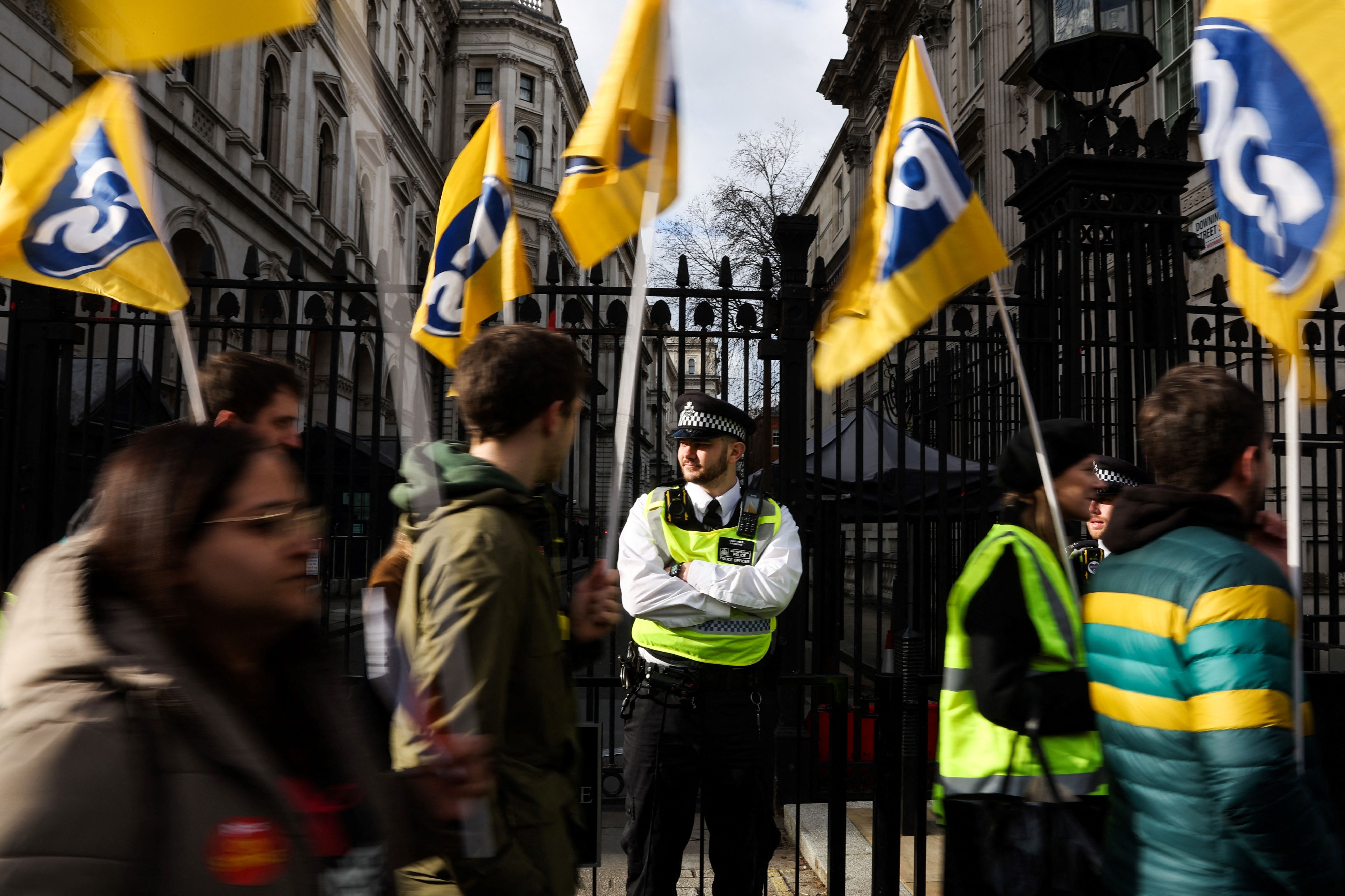 Demonstrators wave flags of the PCS trade union as they march by Downing Street