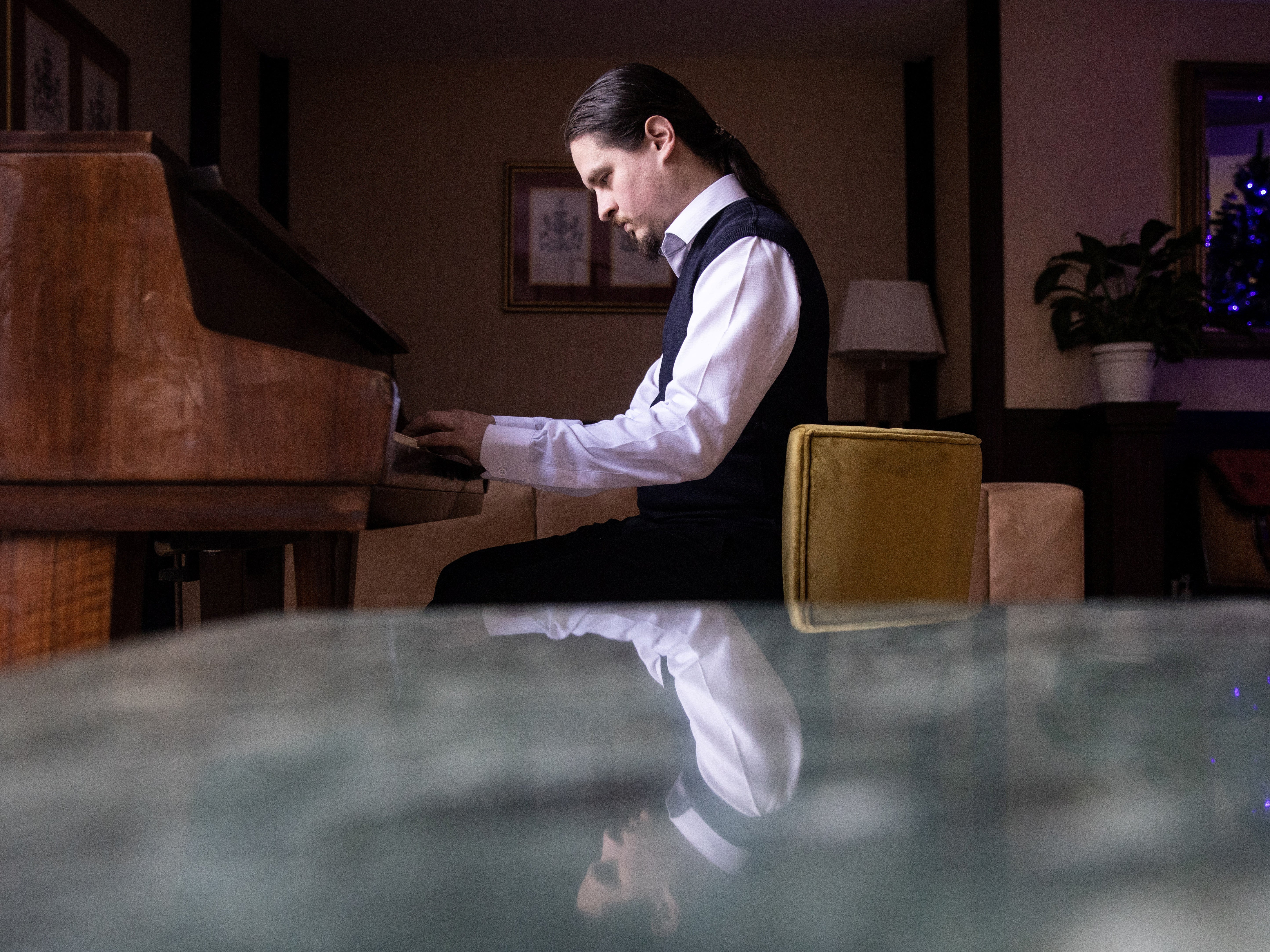 <p>Alexei Antropov, 29, a classical double bassist from Moscow, plays the piano in the lobby of Pino Vere Palace Hotel, where he works as a receptionist in Tbilisi, Georgia</p>
