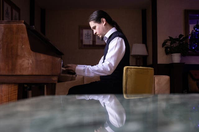 <p>Alexei Antropov, 29, a classical double bassist from Moscow, plays the piano in the lobby of Pino Vere Palace Hotel, where he works as a receptionist in Tbilisi, Georgia</p>