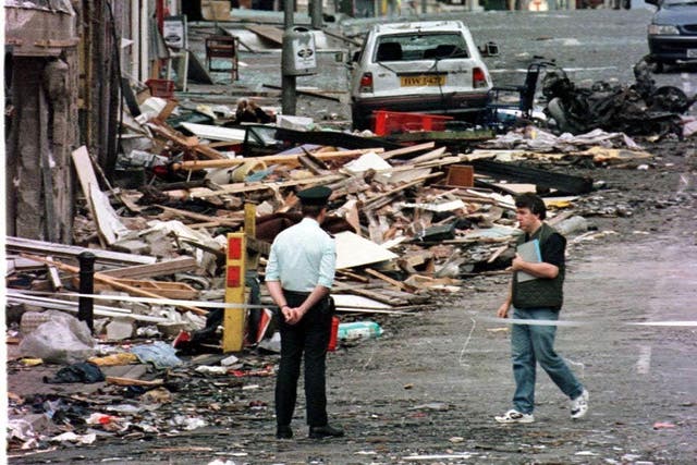 A Royal Ulster Constabulary officer looking at the damage caused by a bomb explosion in Market Street, Omagh in 1998 (PA)