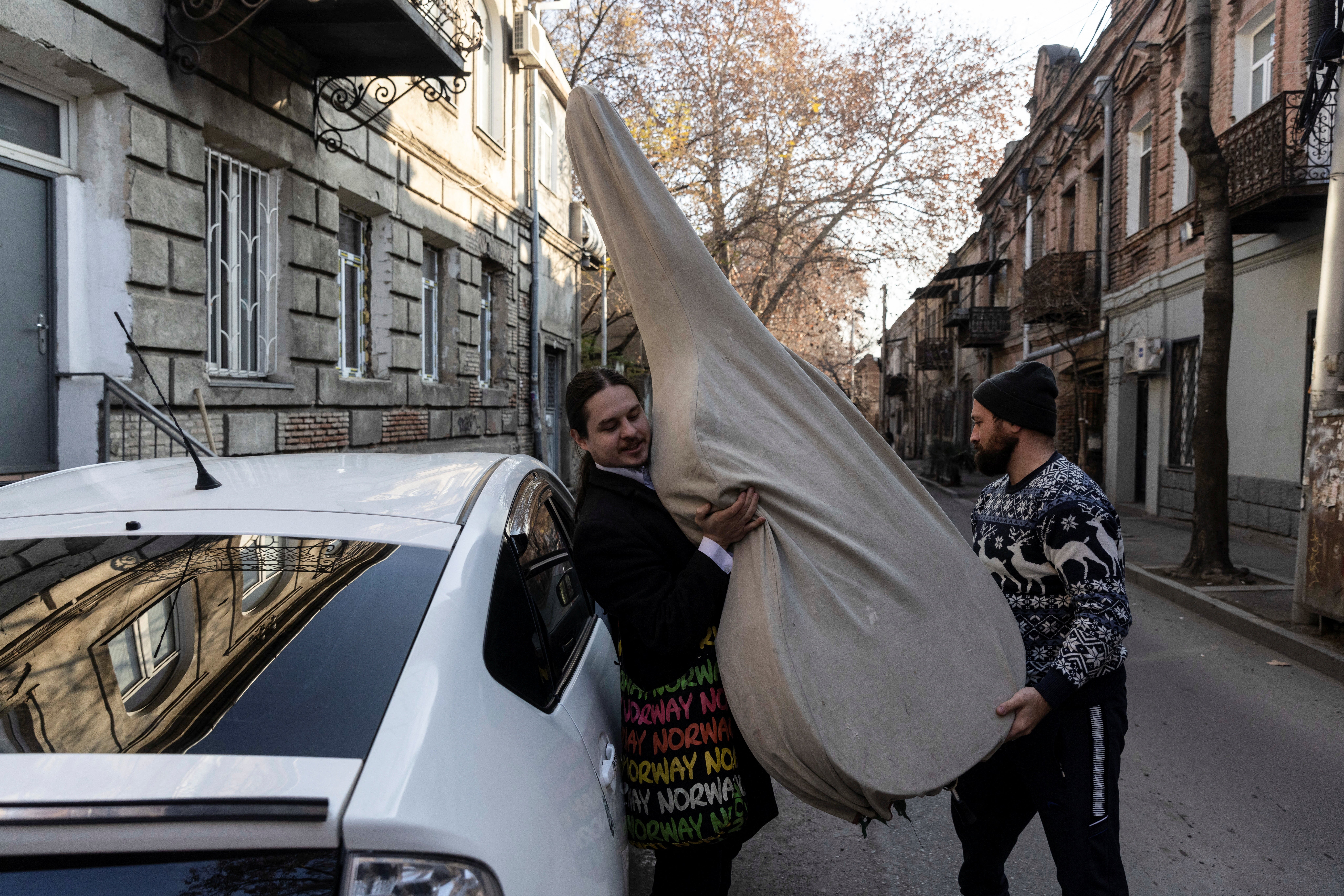 A taxi driver helps Antropov to take out his double bass from the car
