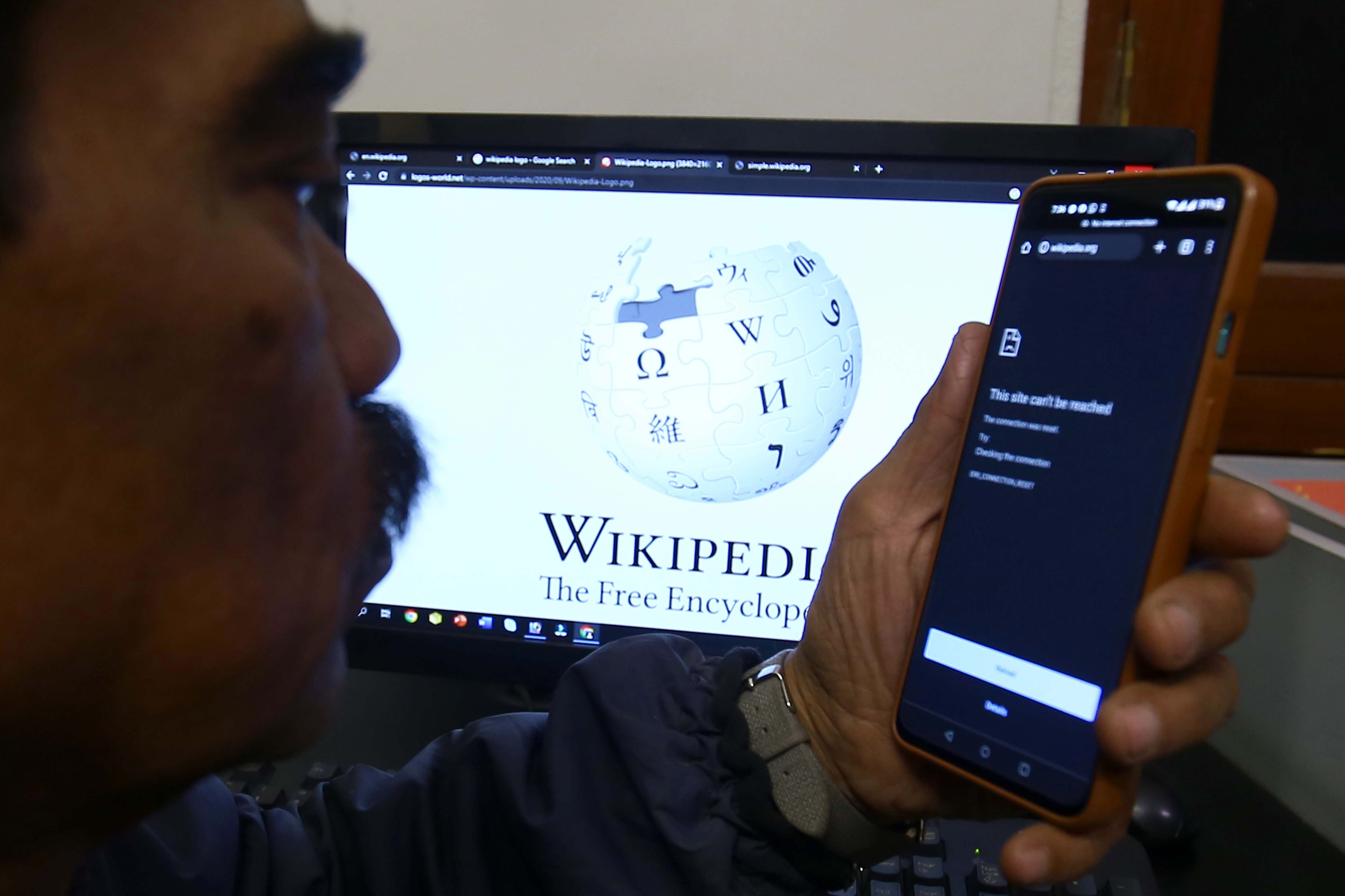 A man in an internet cafe in Karachi can’t access the encyclopaedia on his mobile