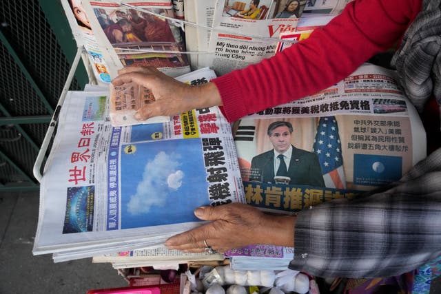 <p>Business owner ‘Annie’ weights down copies of the Chinese Daily News newspaper showcasing pictures of a suspected Chinese spy balloon, in the Chinatown district of Los Angeles</p>