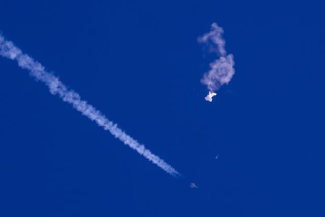 <p>Pictures show remnants of a large balloon drift above the Atlantic Ocean, just off the coast of South Carolina, with a fighter jet and its contrail seen below it</p>