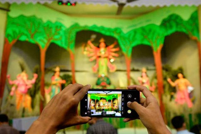 <p>A Bangladeshi hindu devotee takes a picture with a mobile phone during a prayer at the Durga Puja festival at a temple in Dhaka</p>