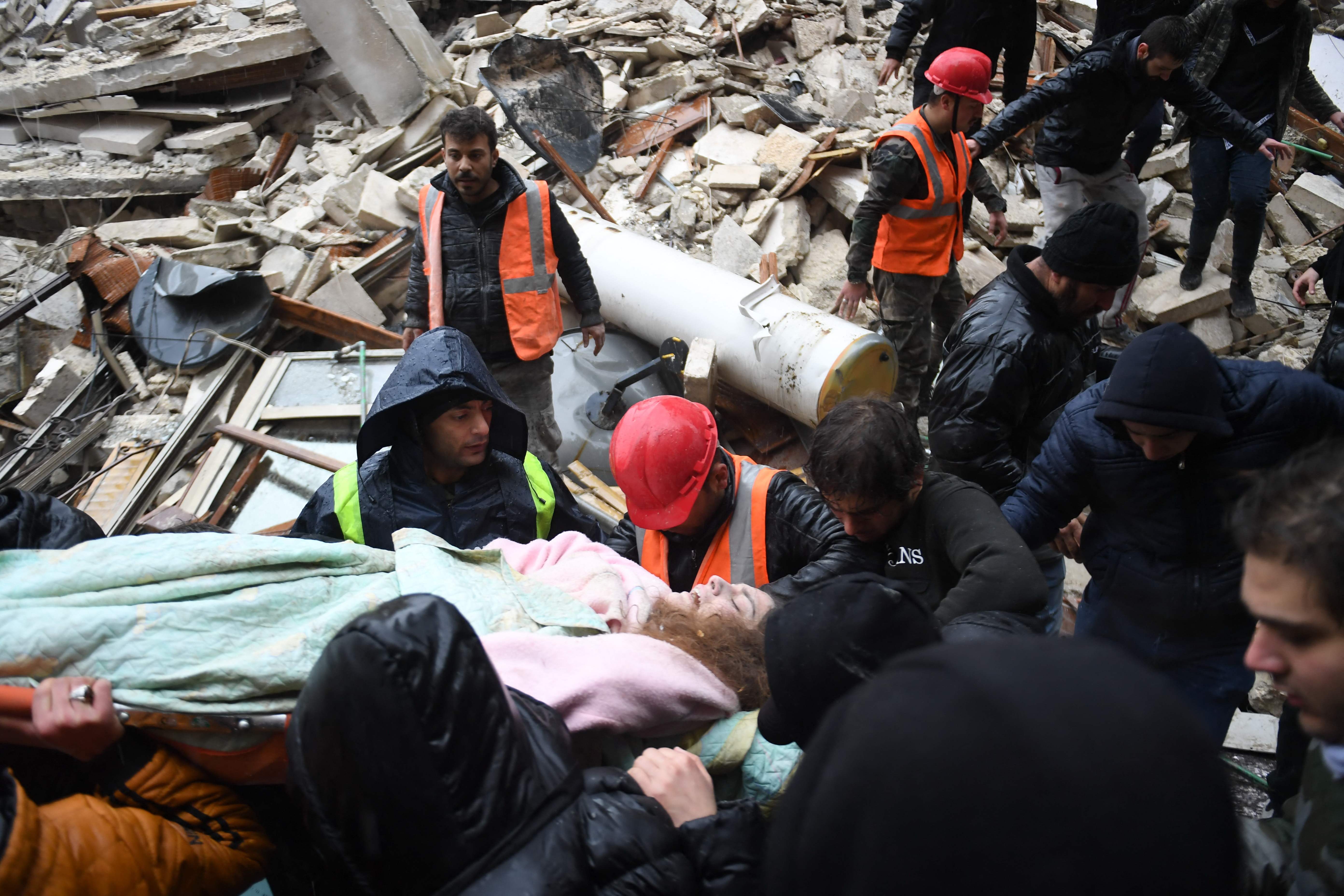 Rescuers carry an injured woman from the rubble of a collapsed building