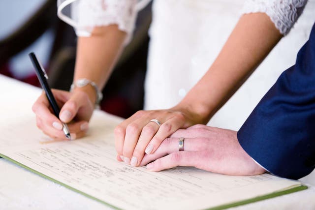 A bride and groom sign a church marriage registration book following their wedding, as new research suggests marriage is good for blood sugar control (Alamy/PA)