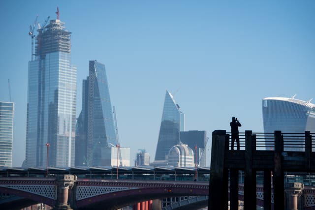 A man takes a photo of the skyline of the City of London (Dominic Lipinski/PA)