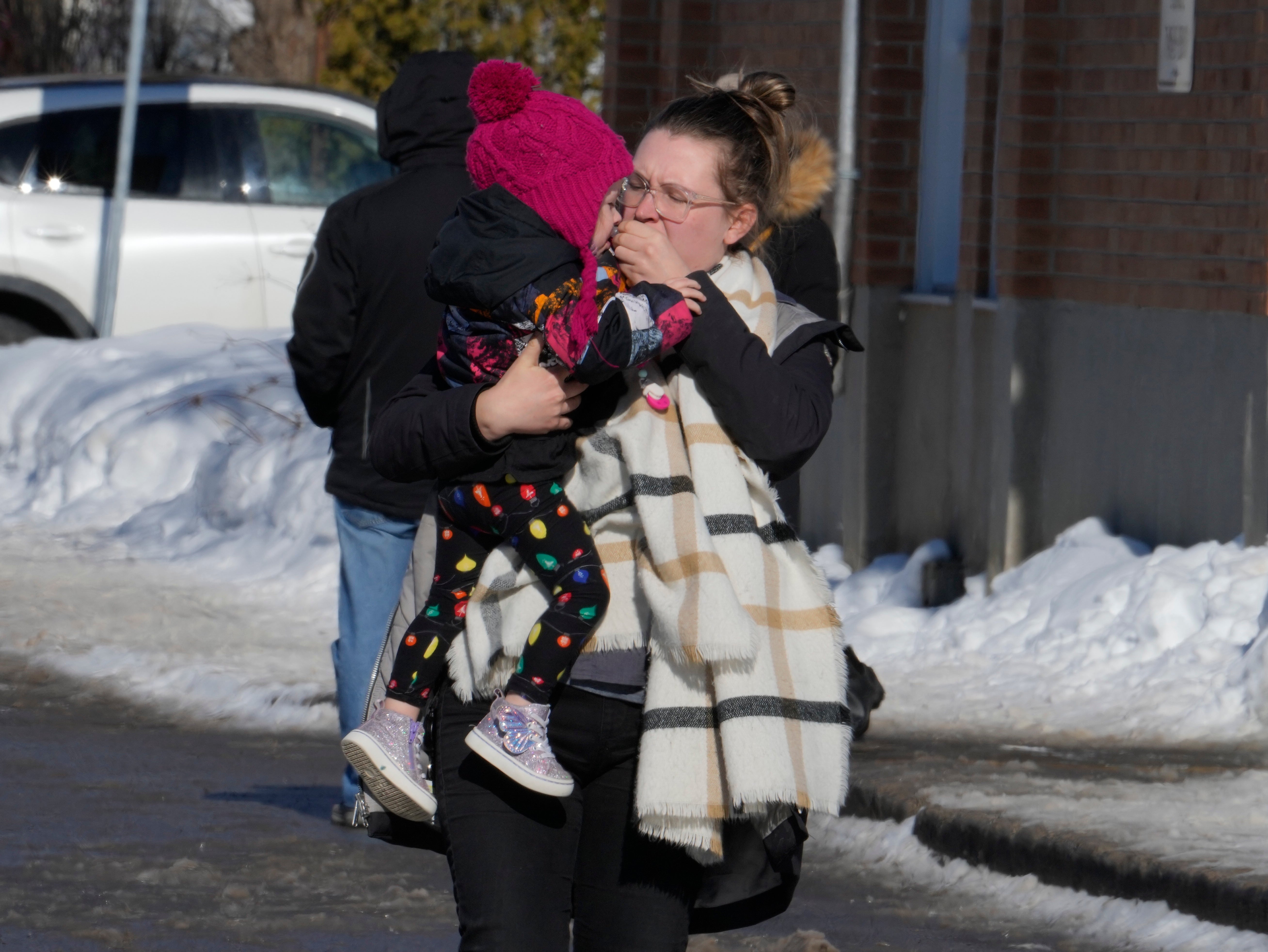 A woman carries a child from a daycare centre after a city bus crashed into the facility in Laval, Quebec, Wednesday, Feb.8, 2023