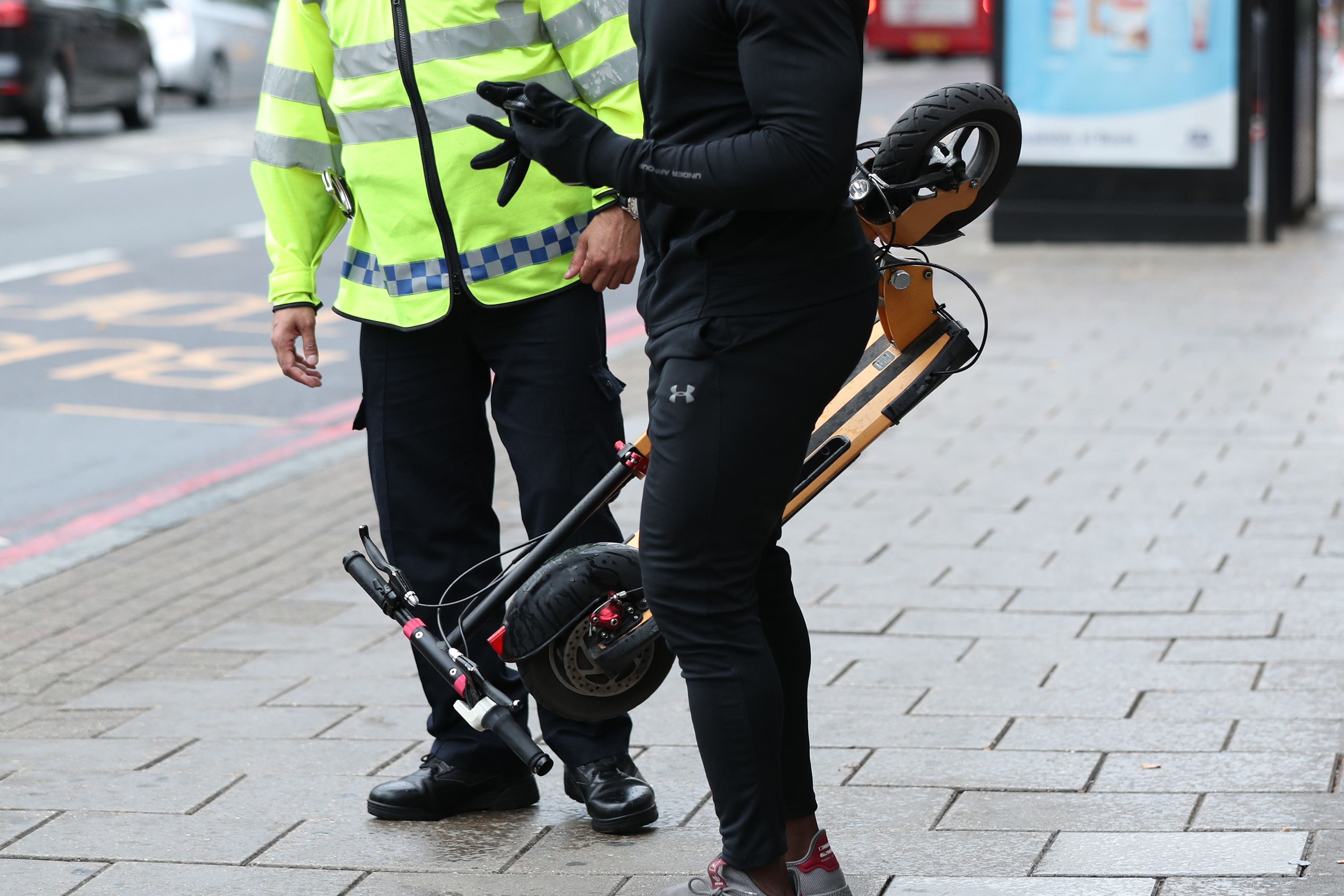 An e-scooter rider is stopped by a police officer in Islington (Yui Mok/PA)