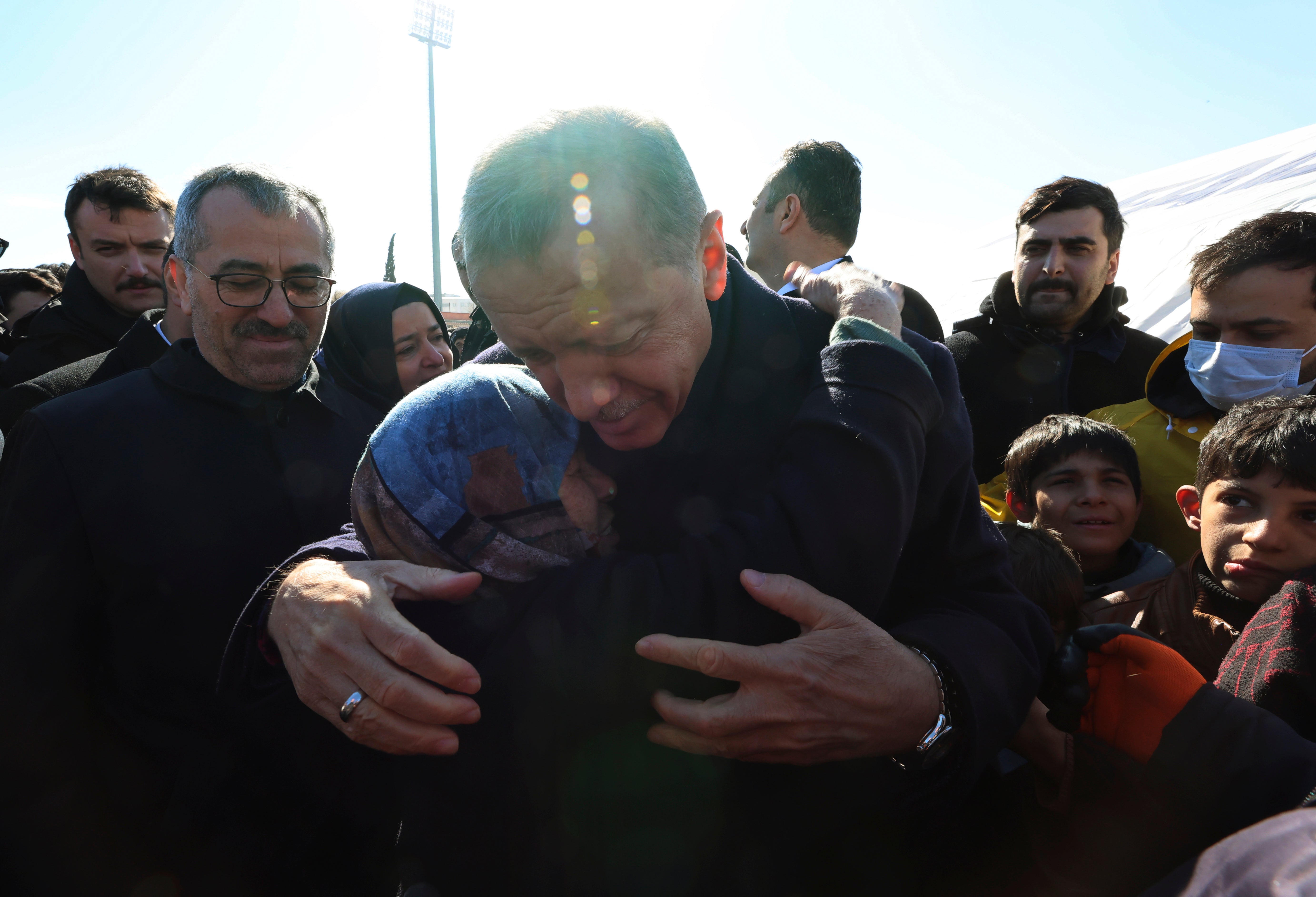 Turkey's President Recep Tayyip Erdogan and a survivor hug each other as he visits the city center destroyed by earthquake