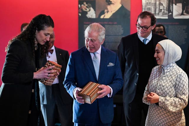 The King attempts to open a puzzle box made in Jordan, during a visit to the newly renovated Leighton House museum in London (Justin Tallis/PA)