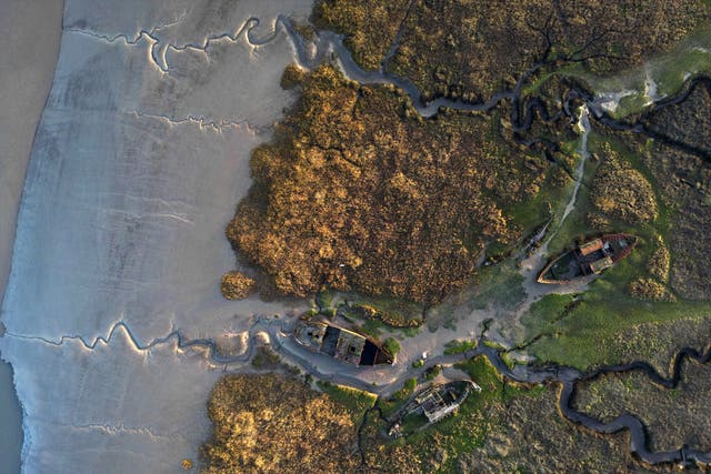 <p>In this aerial view shipwrecked boats sit in a mudbank in the Wyre Estuary</p>