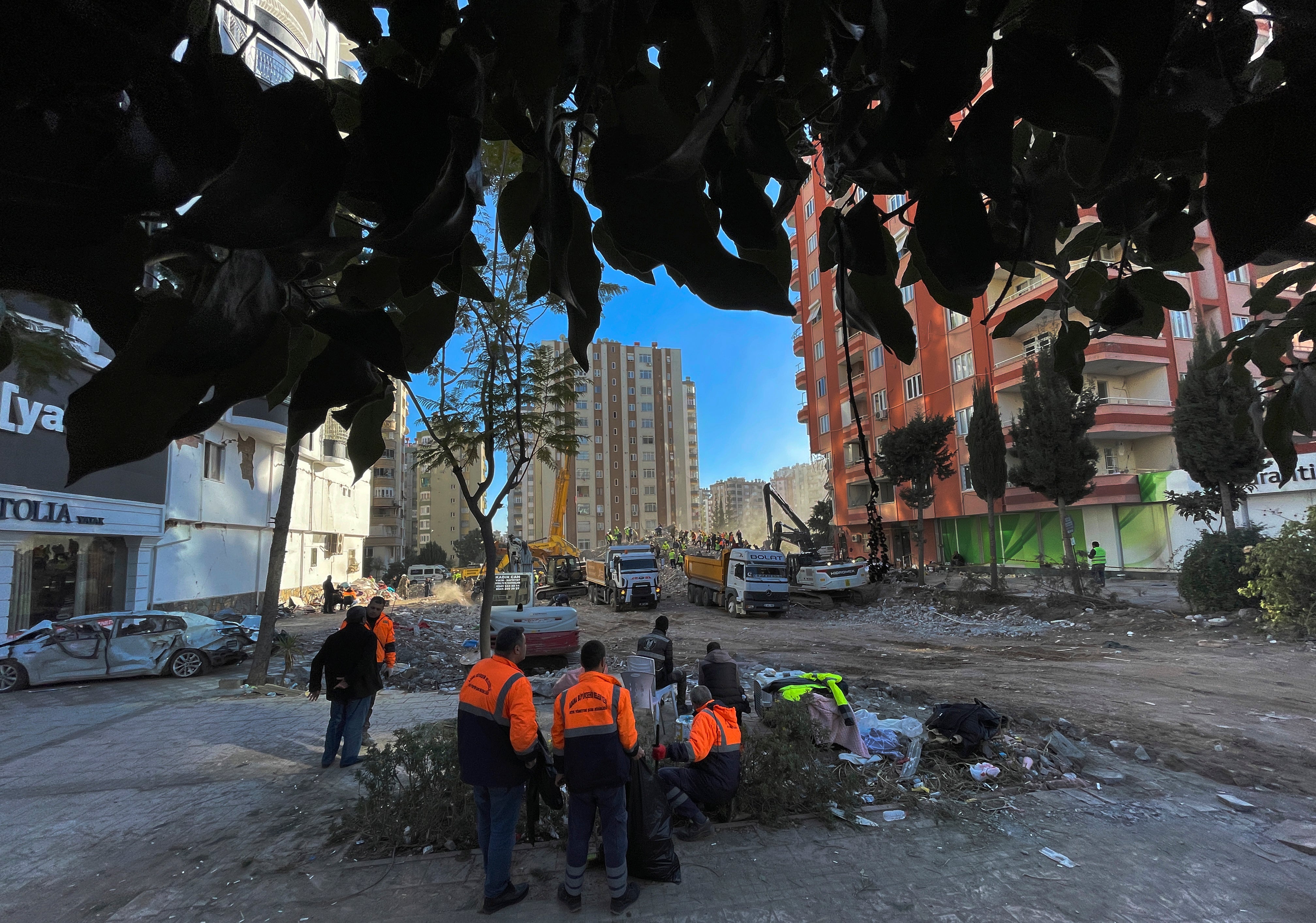 People watch as rescuers search in a destroyed building in Adana, southeastern Turkey