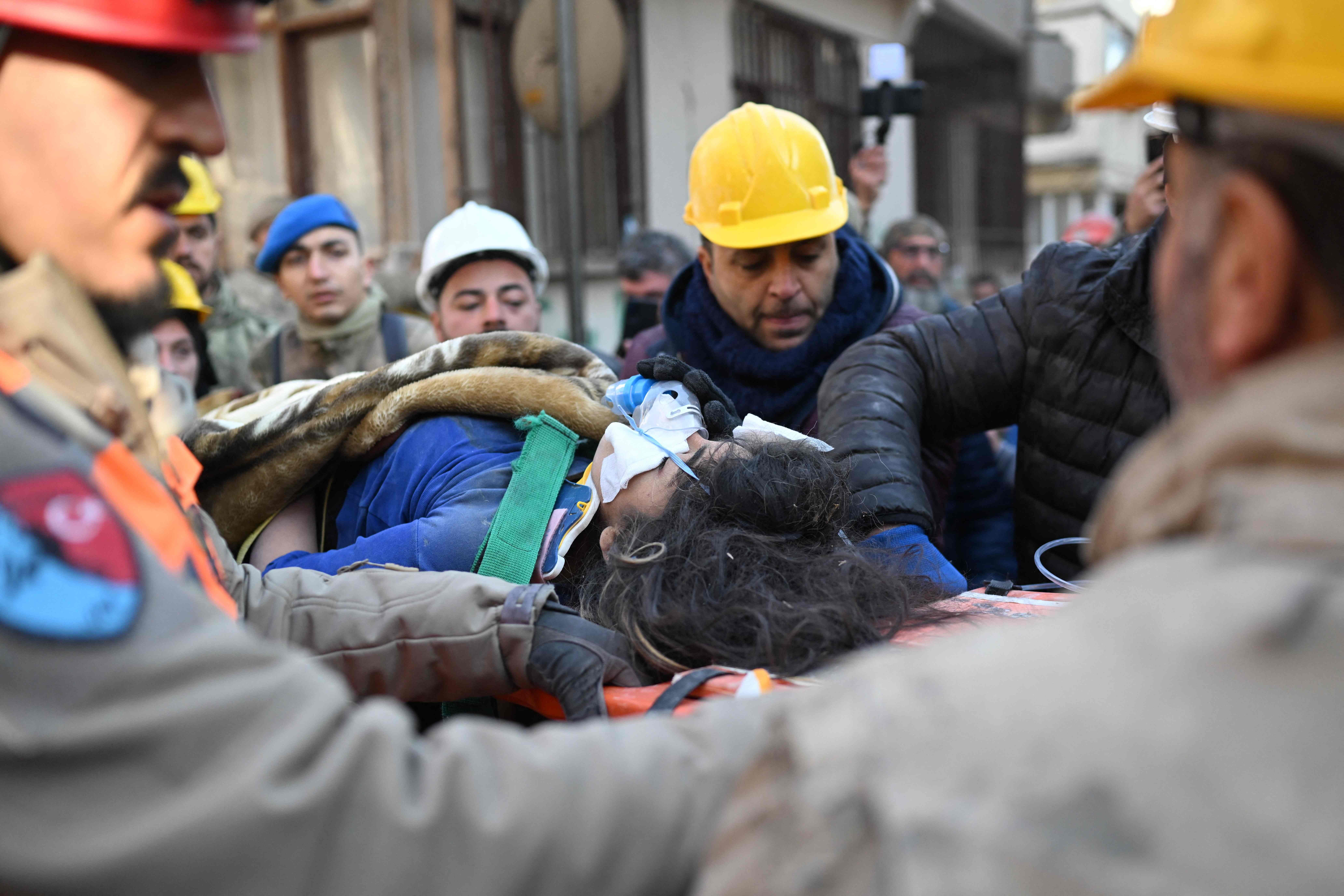 Emergency personnel carry 16-year-old Melda on a stretcher after saving her from the rubble of a collapsed building in Hatay