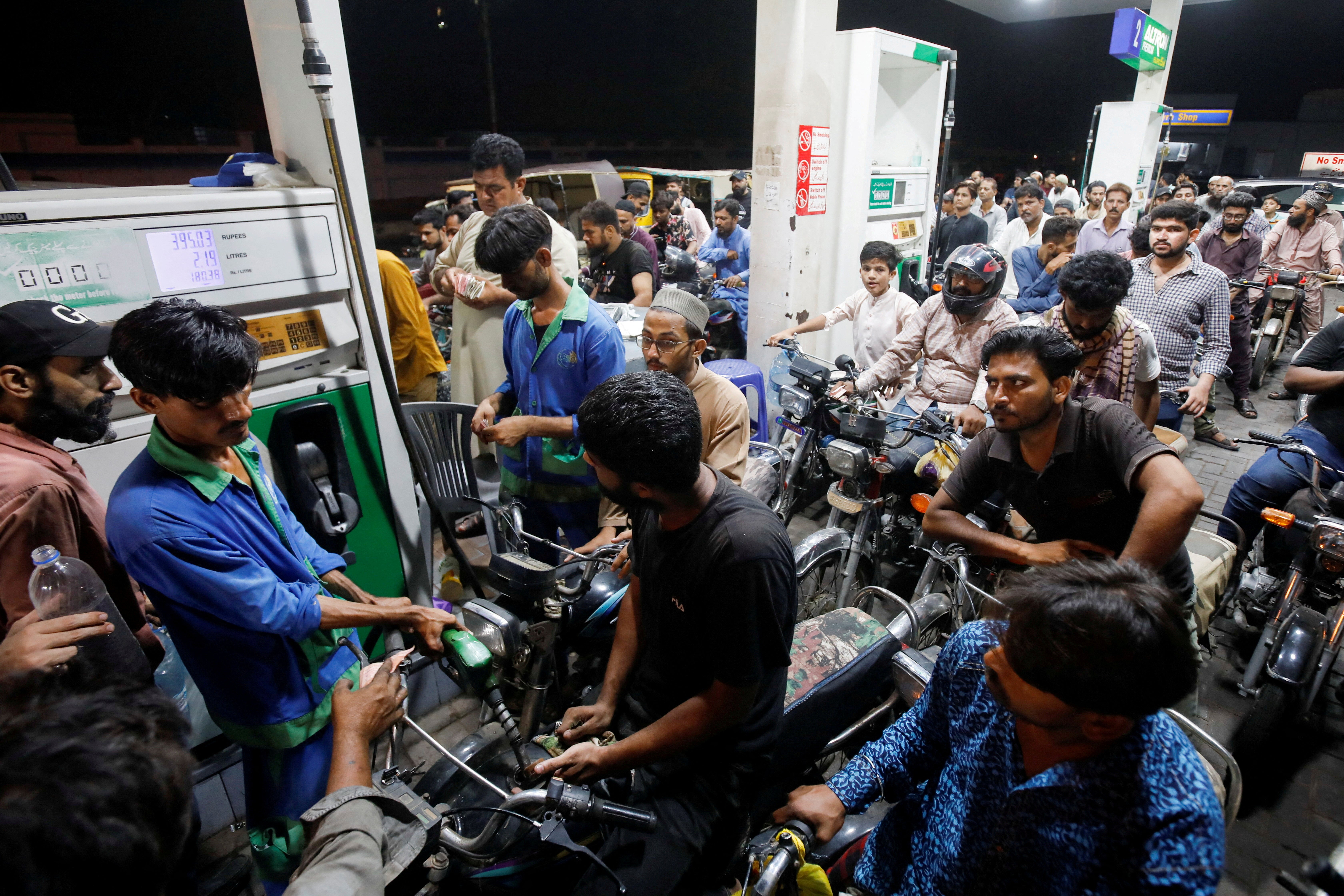 People wait their turn to get fuel at a petrol station, in Karachi