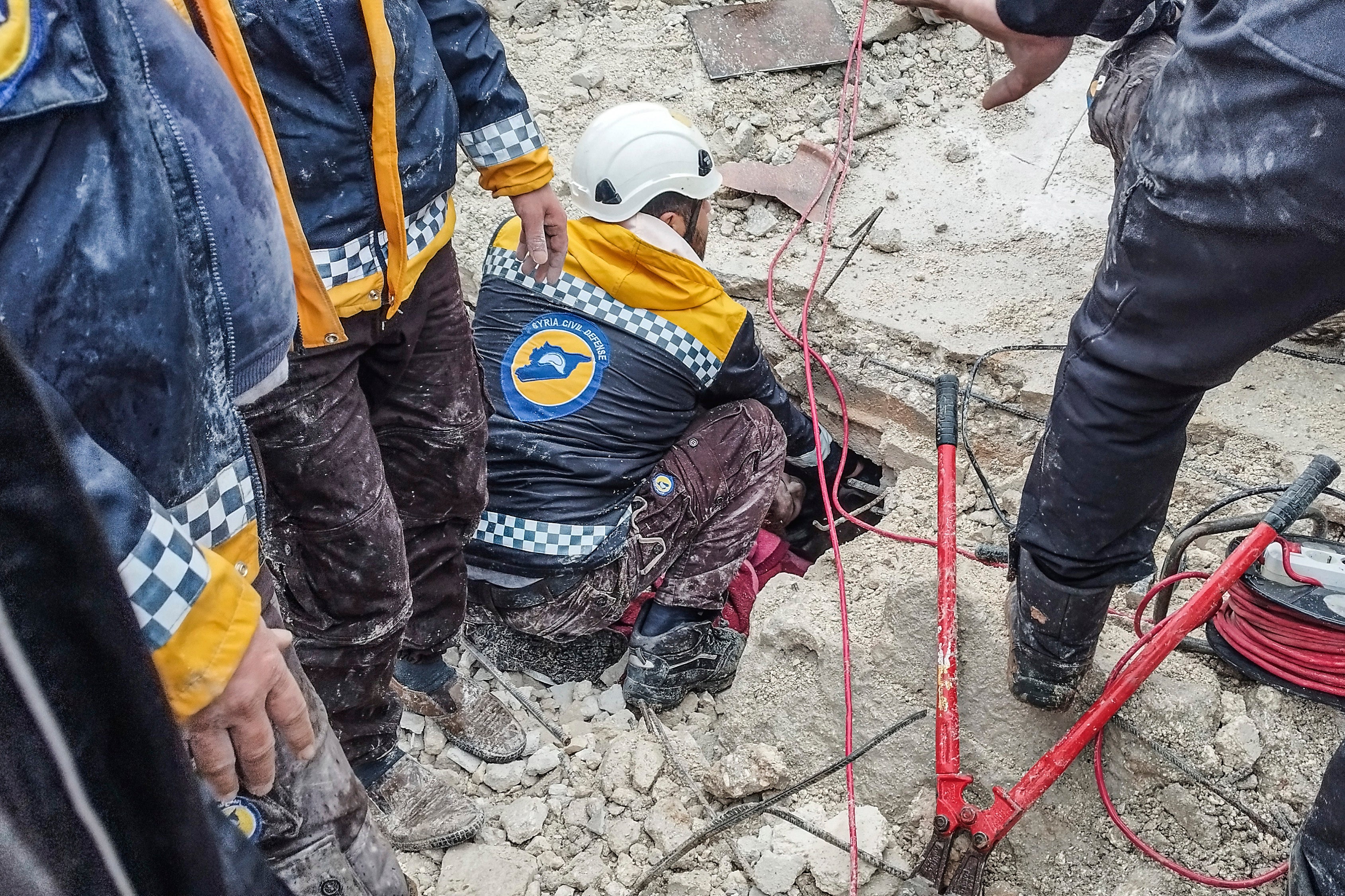 Syrian civil defense members search for people under the rubble of a destroyed building in Afrin