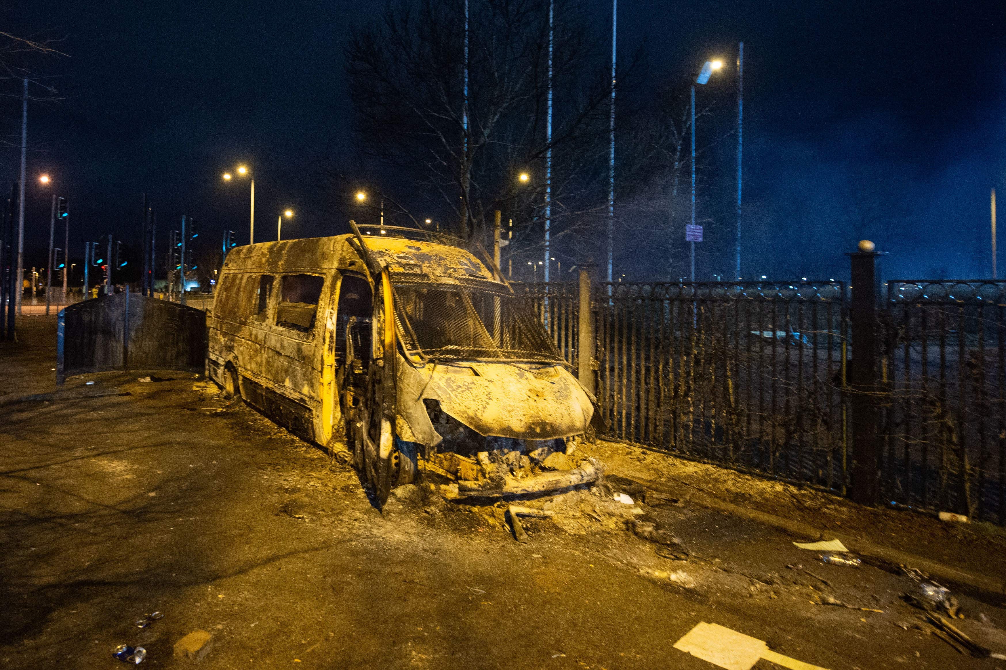 A burnt-out police van after a demonstration outside the Suites Hotel in Knowsley, Merseyside