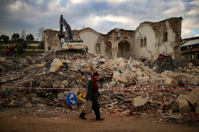 A man walks by a collapsed building in Adiyaman (Emrah Gurel/AP)