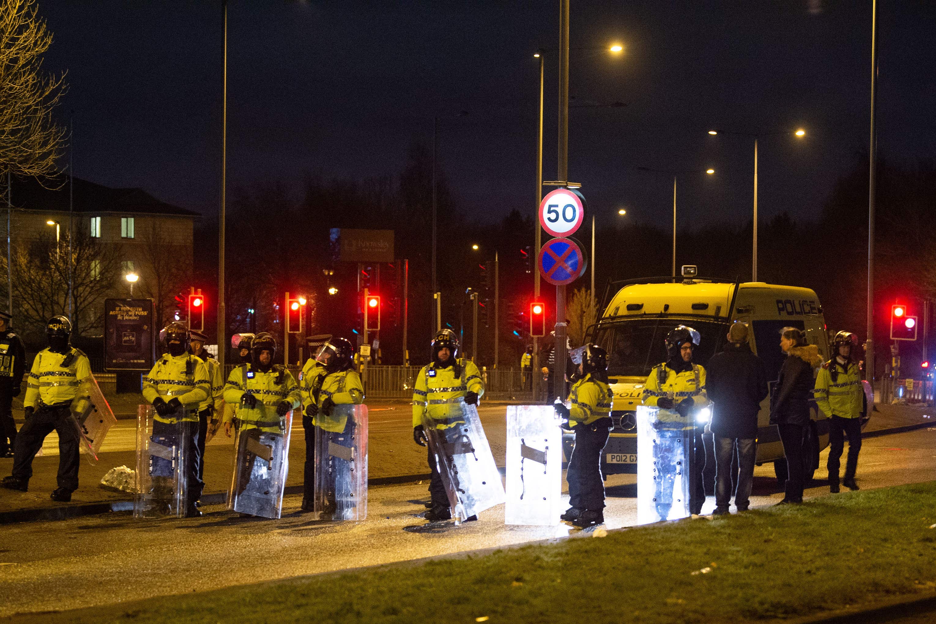 Police in riot gear attend the protest outside the Suites Hotel in Knowsley