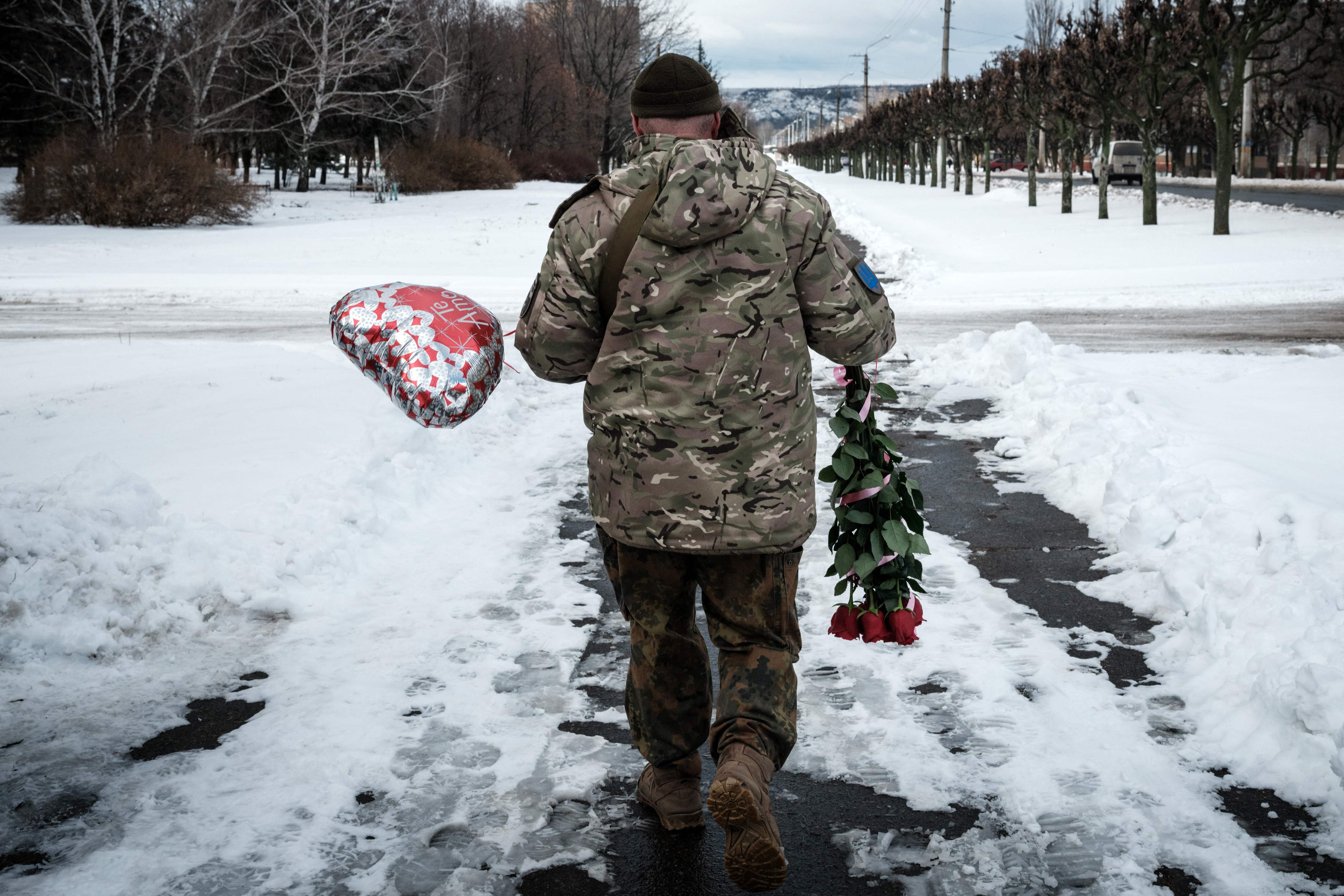 A Ukrainian serviceman walks with flowers and a balloon he bought for Valentines Day in Kramatorsk