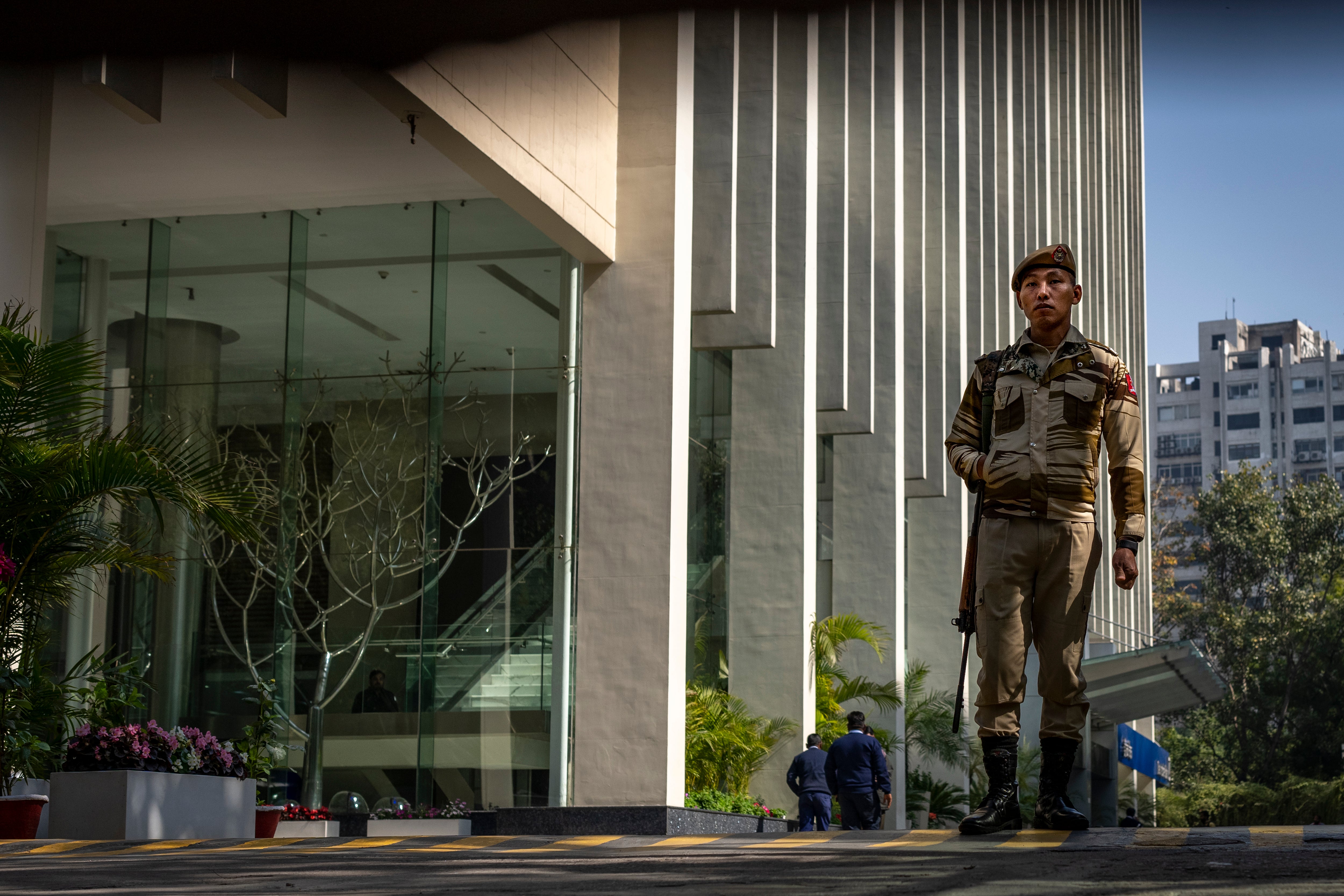 An armed security guard patrols the entrance to a building housing the BBC office in New Delhi, India