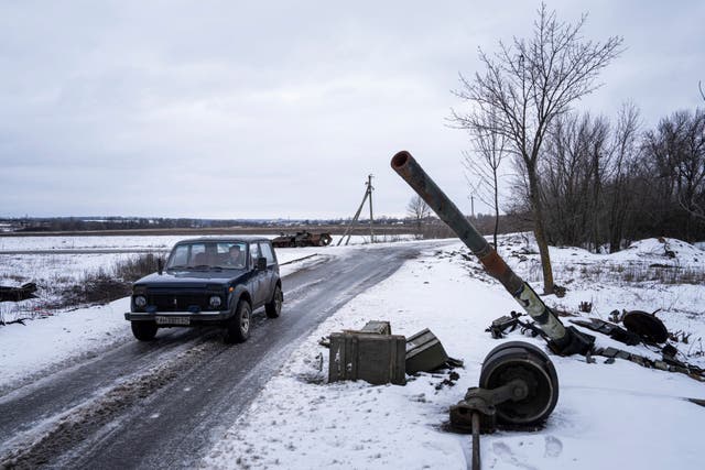 <p>A car drives past a destroyed tank at the former positions of Russian forces in Ridkodub village, Ukraine</p>