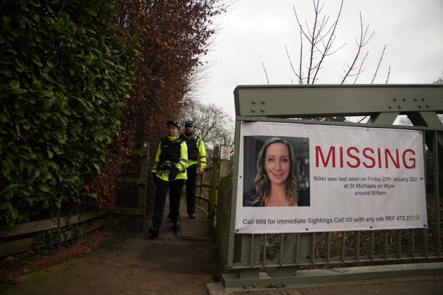 Police officers walk towards a missing person appeal poster for Nicola Bulley on a bridge over the River Wyre in St Michael’s on Wyre, Lancashire (Peter Byrne/PA)