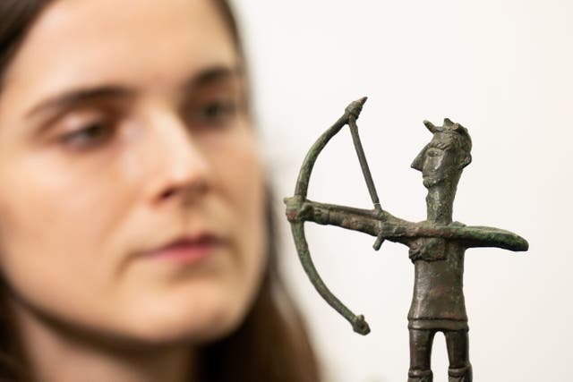 Olivia Maguire inspects a bronze figurine of an archer excavated at the Iron Age sanctuary of Abini Teti, Sardinia (Joe Giddens/PA)