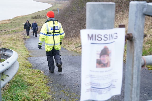 <p>A member of the police search and rescue team waits at Shard Bridge for a boat to come down the River Wyre in Lancashire</p>