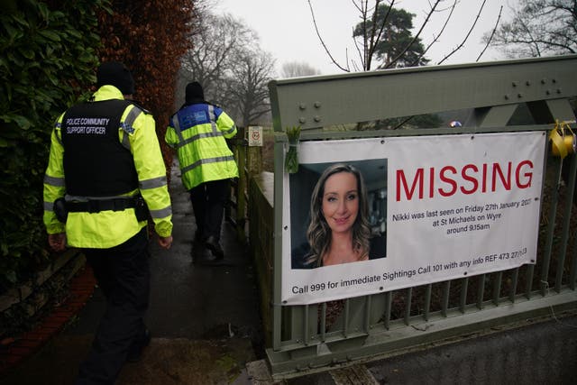<p>Police officers walk past a missing person appeal poster for Nicola Bulley tied to a bridge over the River Wyre in St Michael’s on Wyre, Lancashire (Peter Byrne/PA)</p>