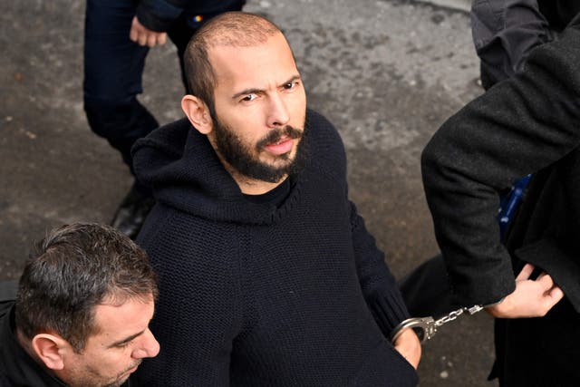 <p>British-US influencer Andrew Tate arrives handcuffed and escorted by police at a courthouse in Bucharest on 1 February</p>
