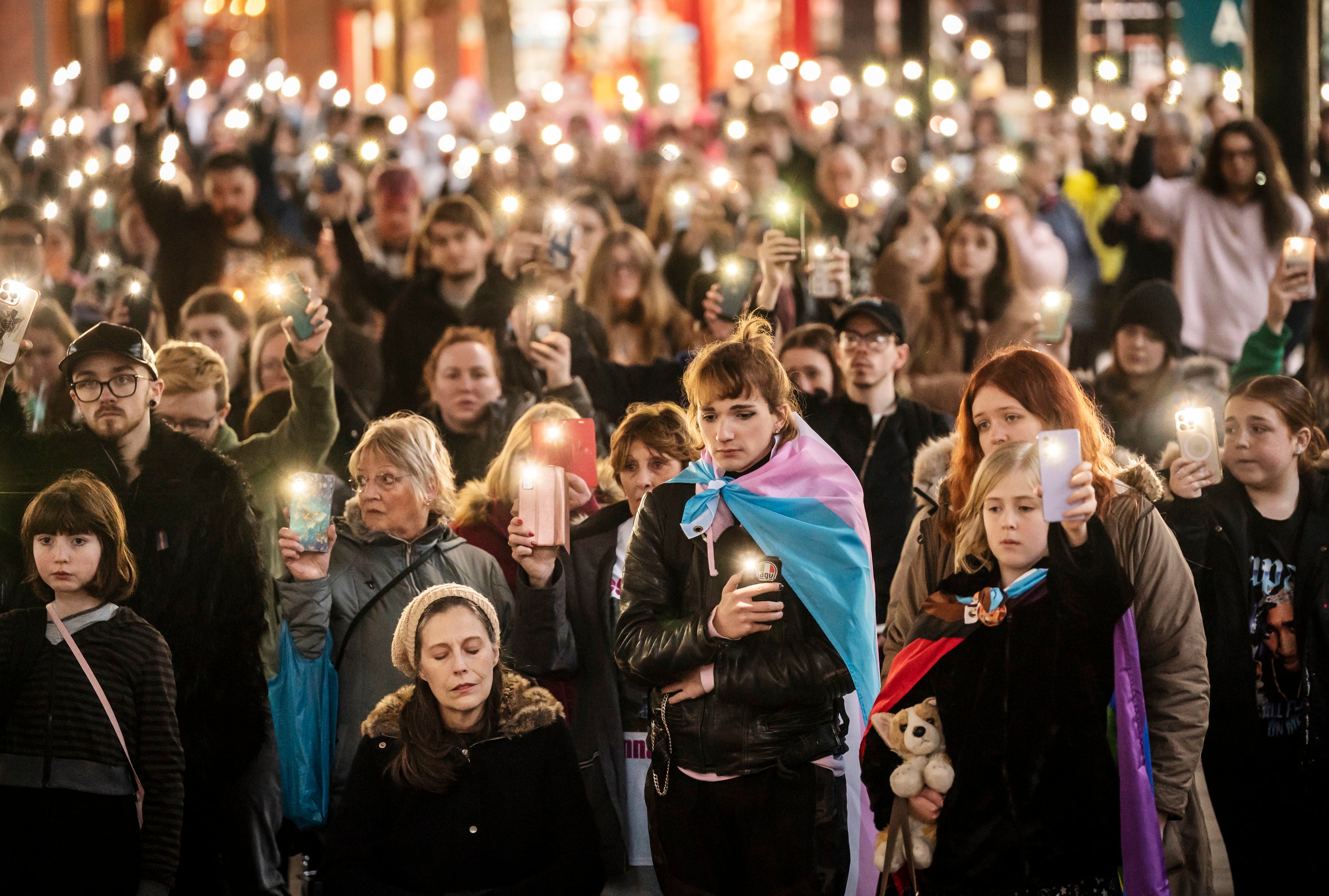 Members of the public hold their phones with the torch function set during a moment of silence as they attend a candle-lit vigil at Old Market Place in Warrington in memory of transgender teenager Brianna Ghey