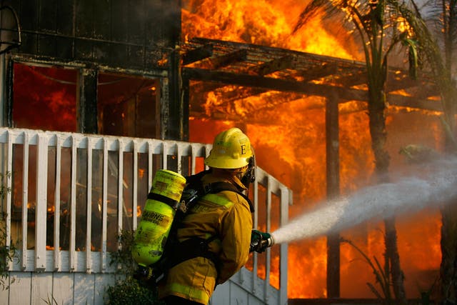 <p>A US forestry firefighter cools a burning modular home to protect a nearby structure in Deerhorn Valley as the Harris Fire continues growing beyond 70,000 acres on October 24, 2007 near Jamul, California</p>