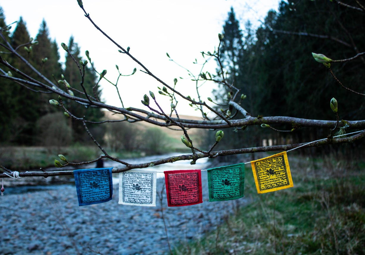 Tibetan prayer flags hanging by the river in the spring at Samye Ling Buddhist Monastery